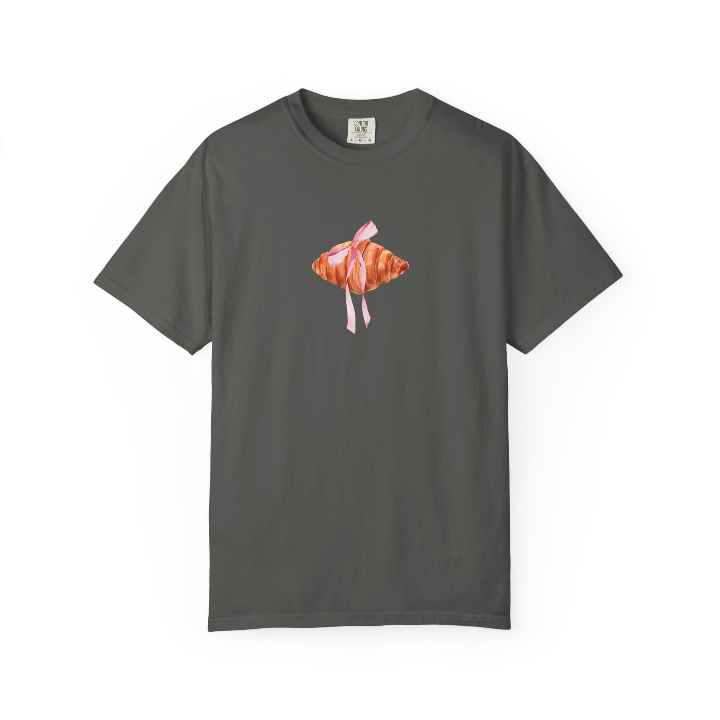 T-shirt with watercolor croissant design featuring golden brown pastry with pink ribbon bow
