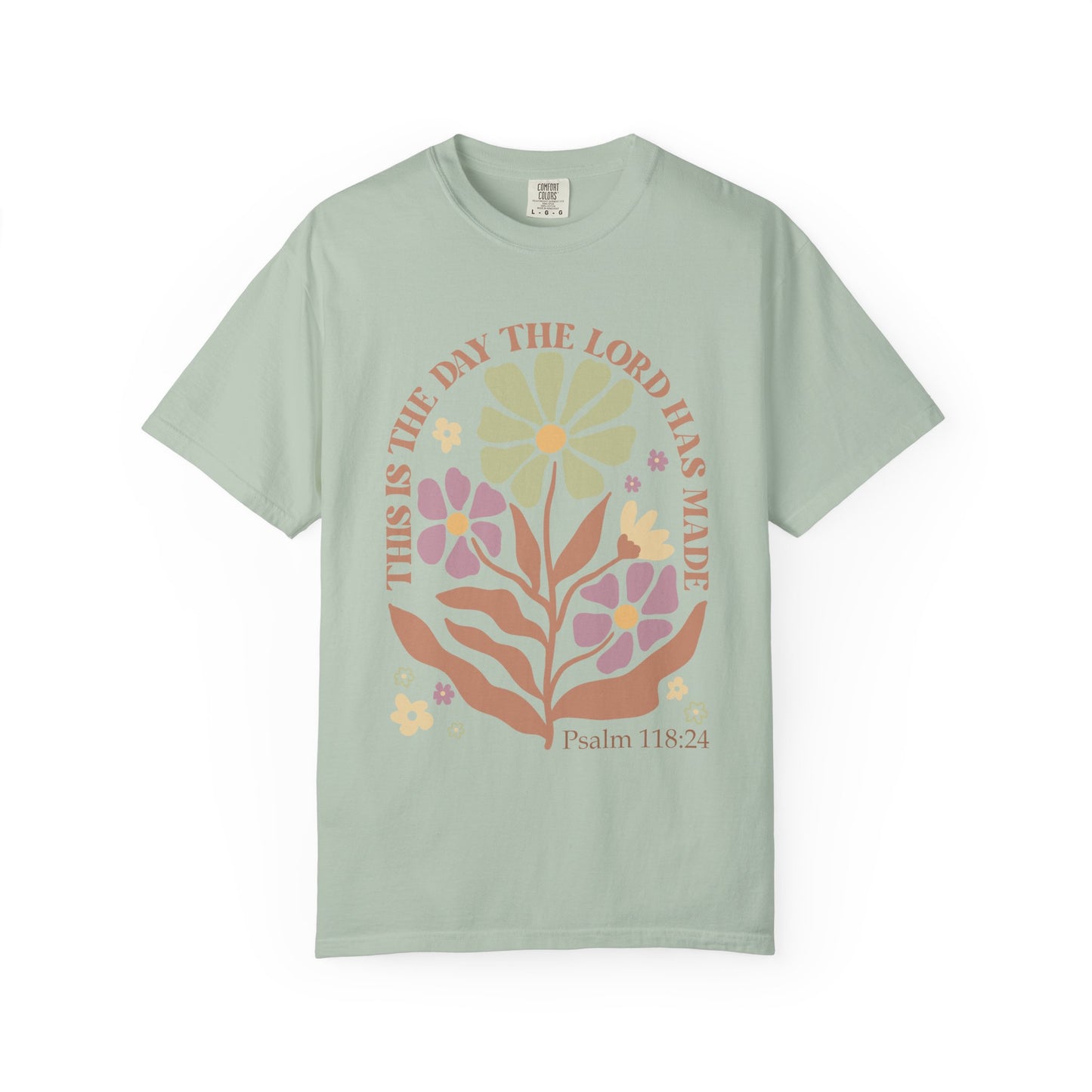 T-shirt with 'This is the Day' text, Psalm 118:24 verse, and floral design with protective hands in sage green, pink, and terracotta colors