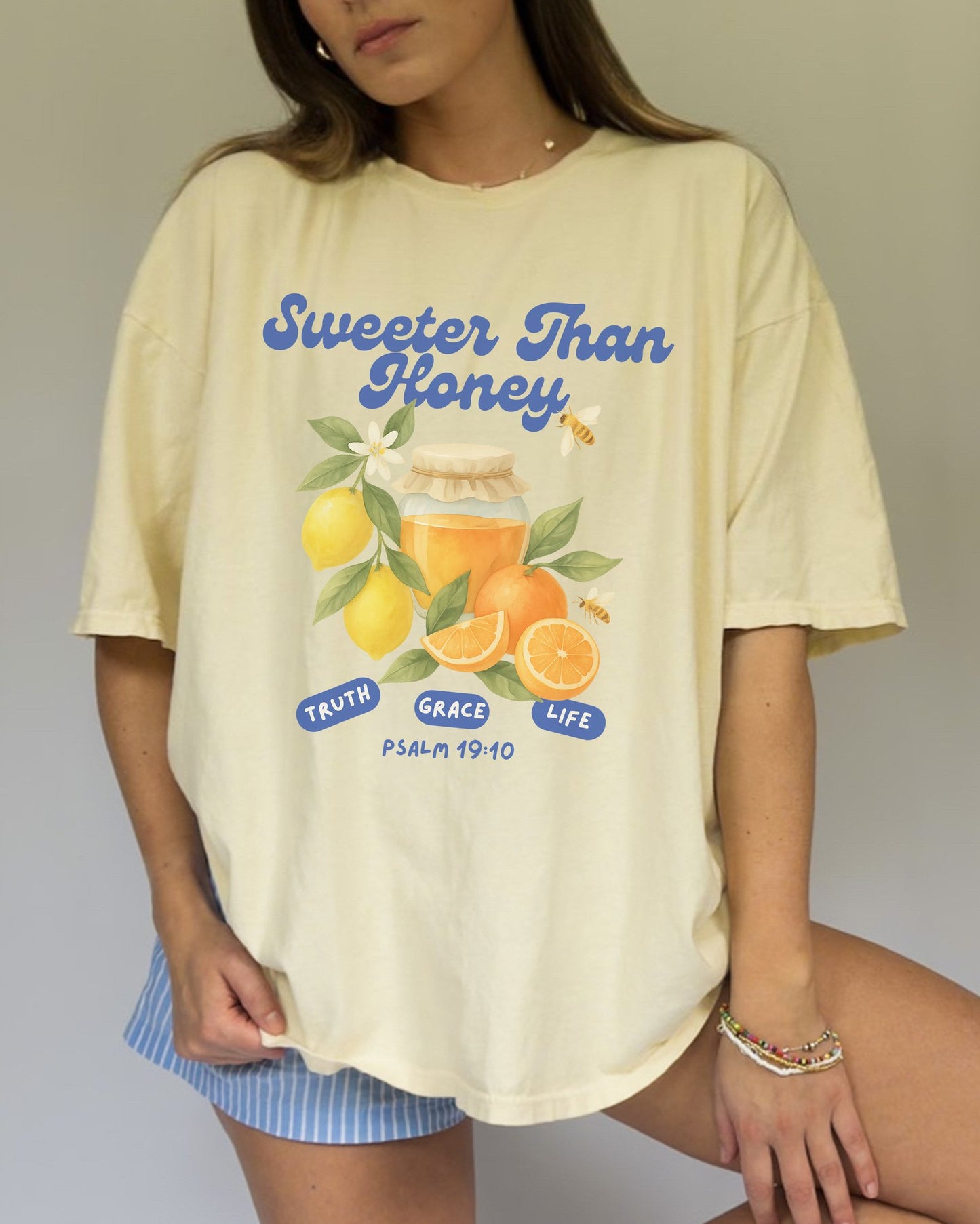 Christian t-shirt with Sweeter Than Honey Psalm 19:10 design featuring watercolor honey jar, citrus fruits, and bees