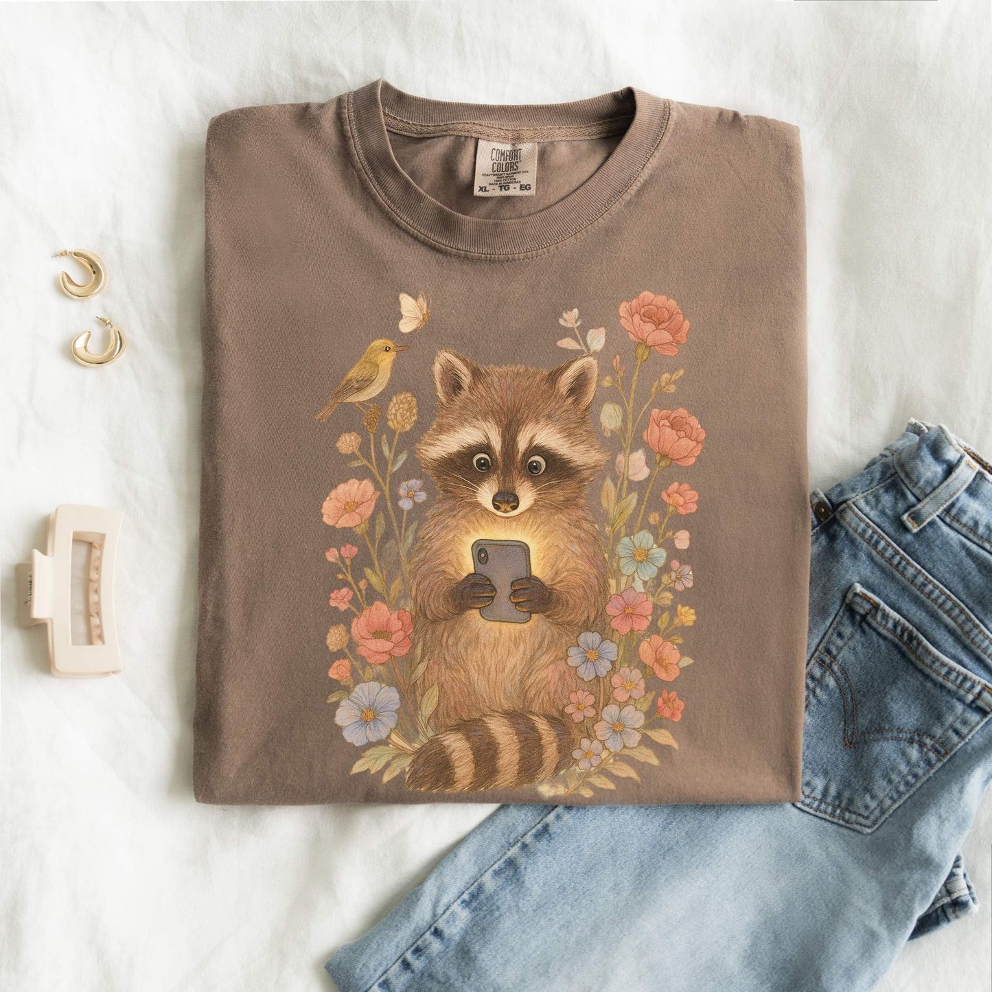 T-shirt with cute raccoon holding smartphone surrounded by coral and blue wildflowers