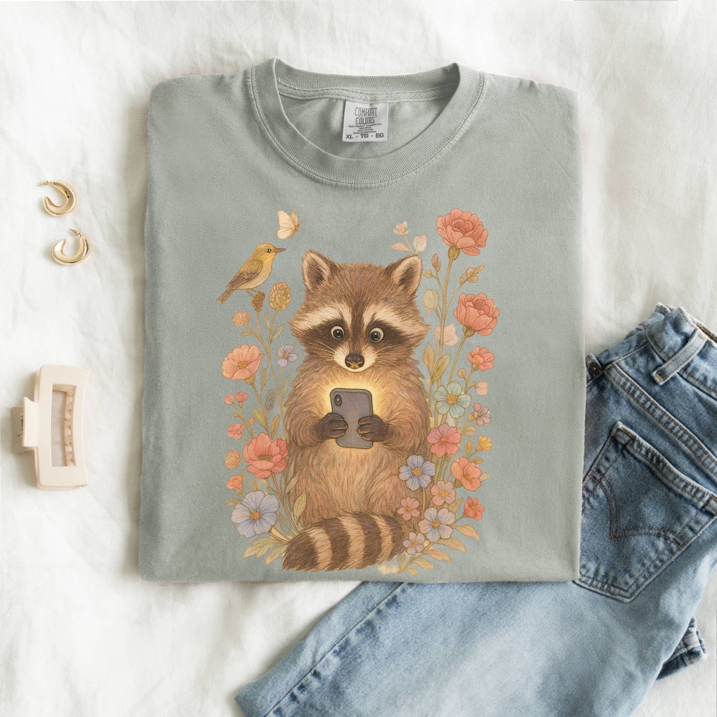 T-shirt with cute raccoon holding smartphone surrounded by coral and blue wildflowers