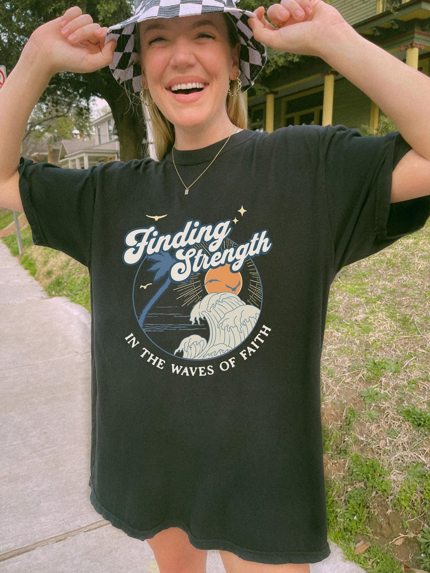 T-shirt with retro Christian design featuring palm tree, sunset, and ocean waves with Finding Strength text