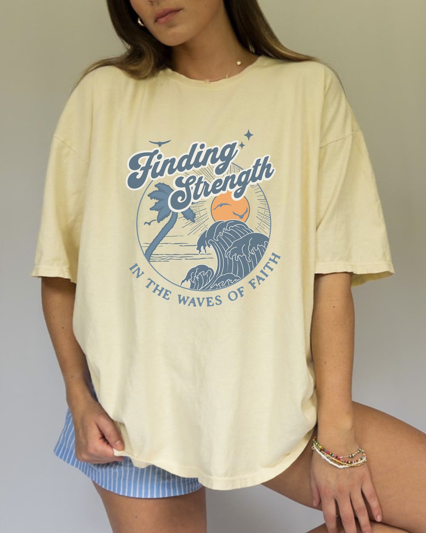 T-shirt with retro Christian design featuring palm tree, sunset, and ocean waves with Finding Strength text