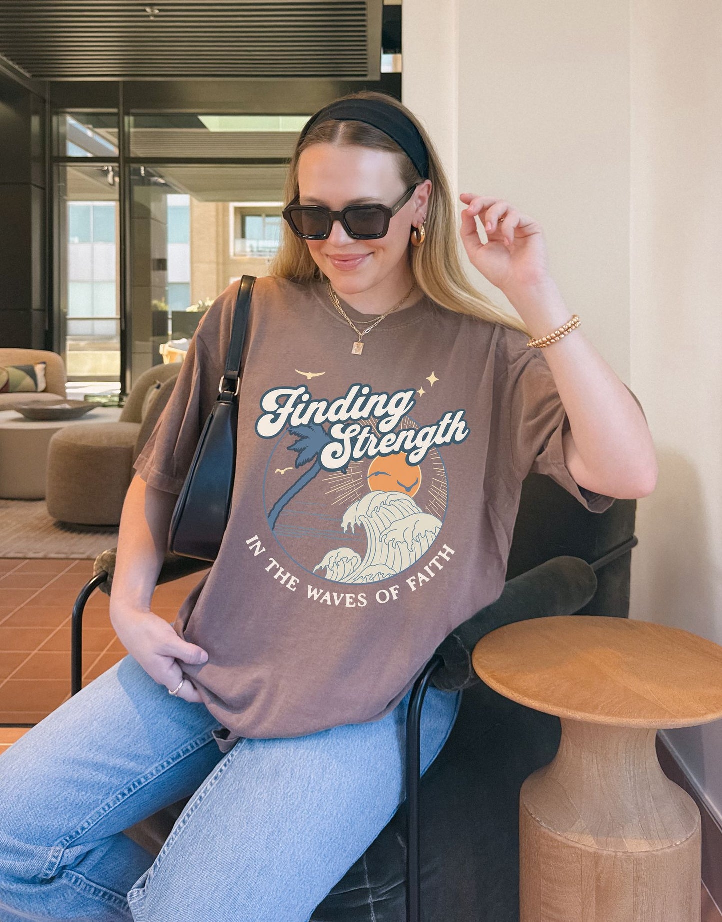 T-shirt with retro Christian design featuring palm tree, sunset, and ocean waves with Finding Strength text