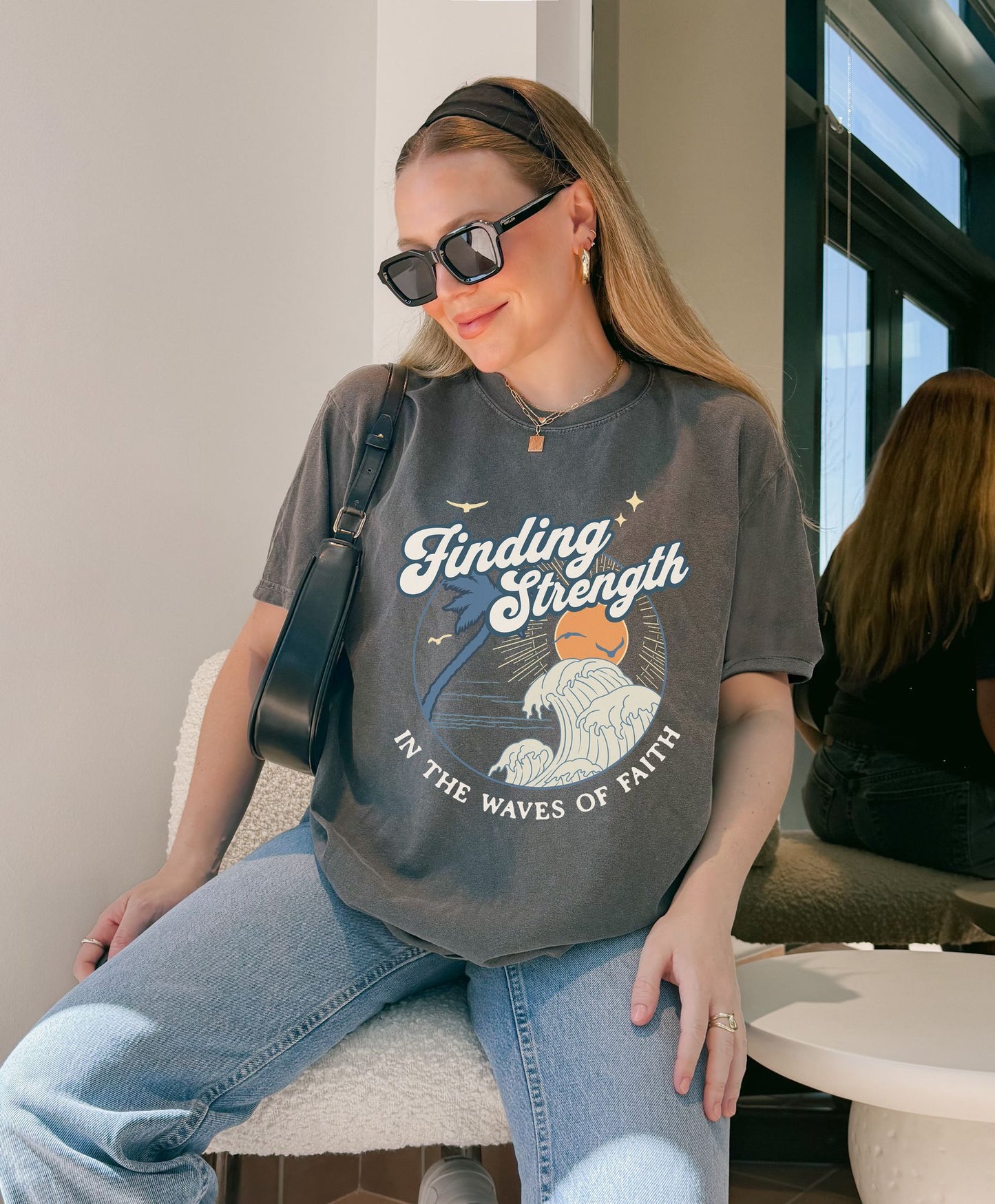 T-shirt with retro Christian design featuring palm tree, sunset, and ocean waves with Finding Strength text