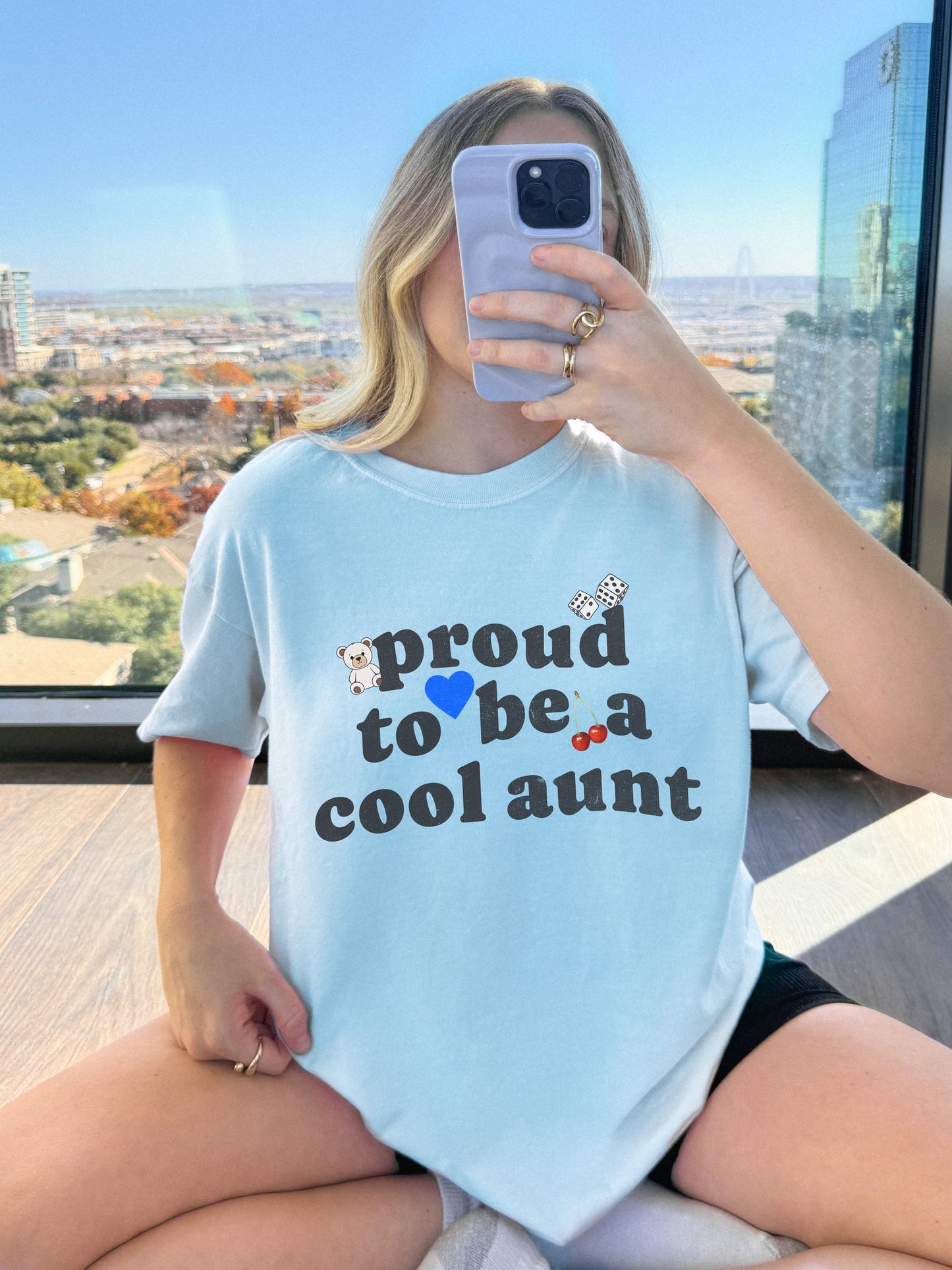 T-shirt with retro distressed text 'proud to be a cool aunt' decorated with teddy bear, blue heart, dice, and cherries