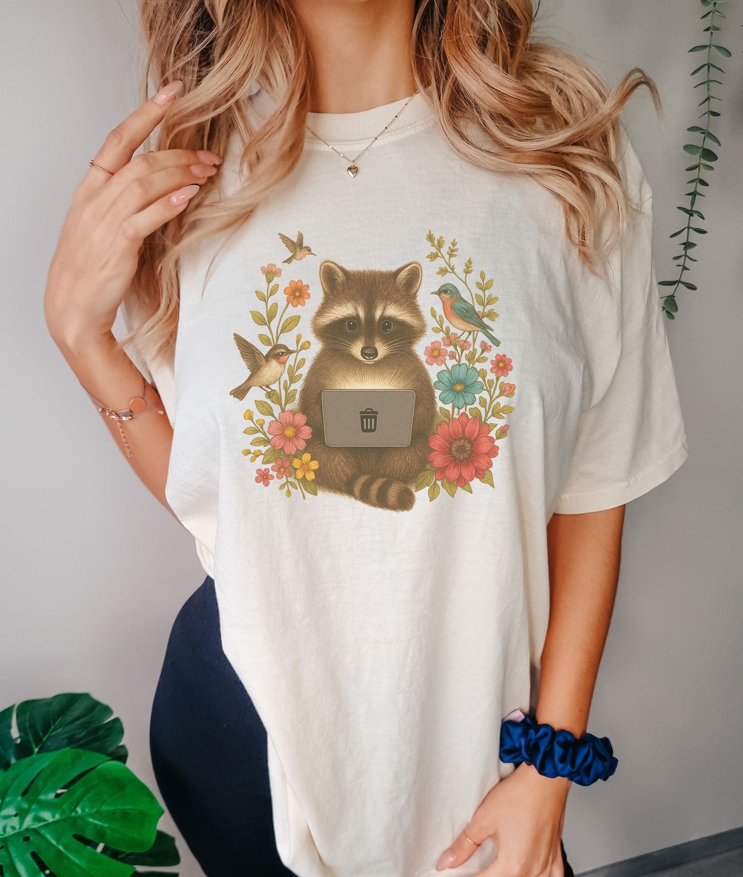 T-shirt with vintage-style raccoon illustration surrounded by colorful wildflowers and birds
