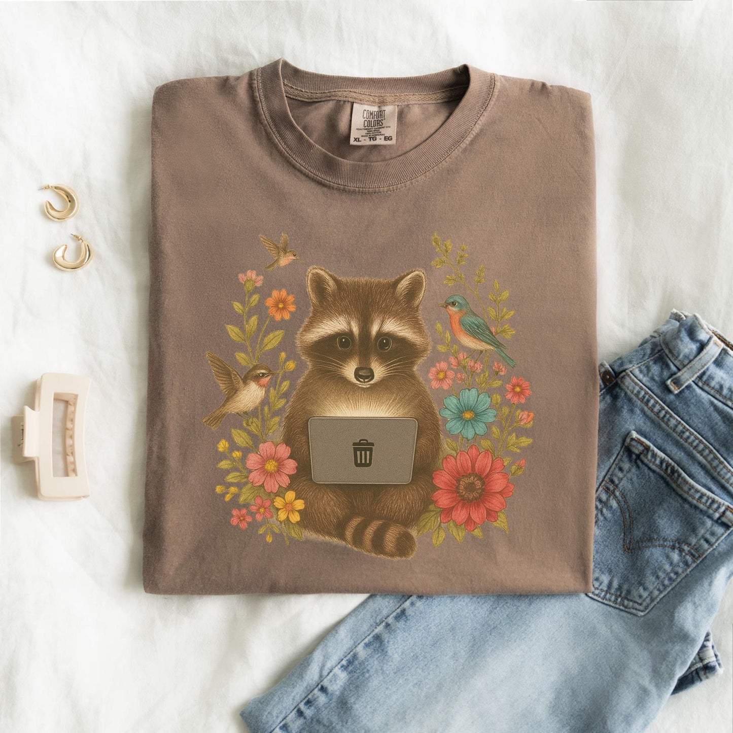 T-shirt with vintage-style raccoon illustration surrounded by colorful wildflowers and birds