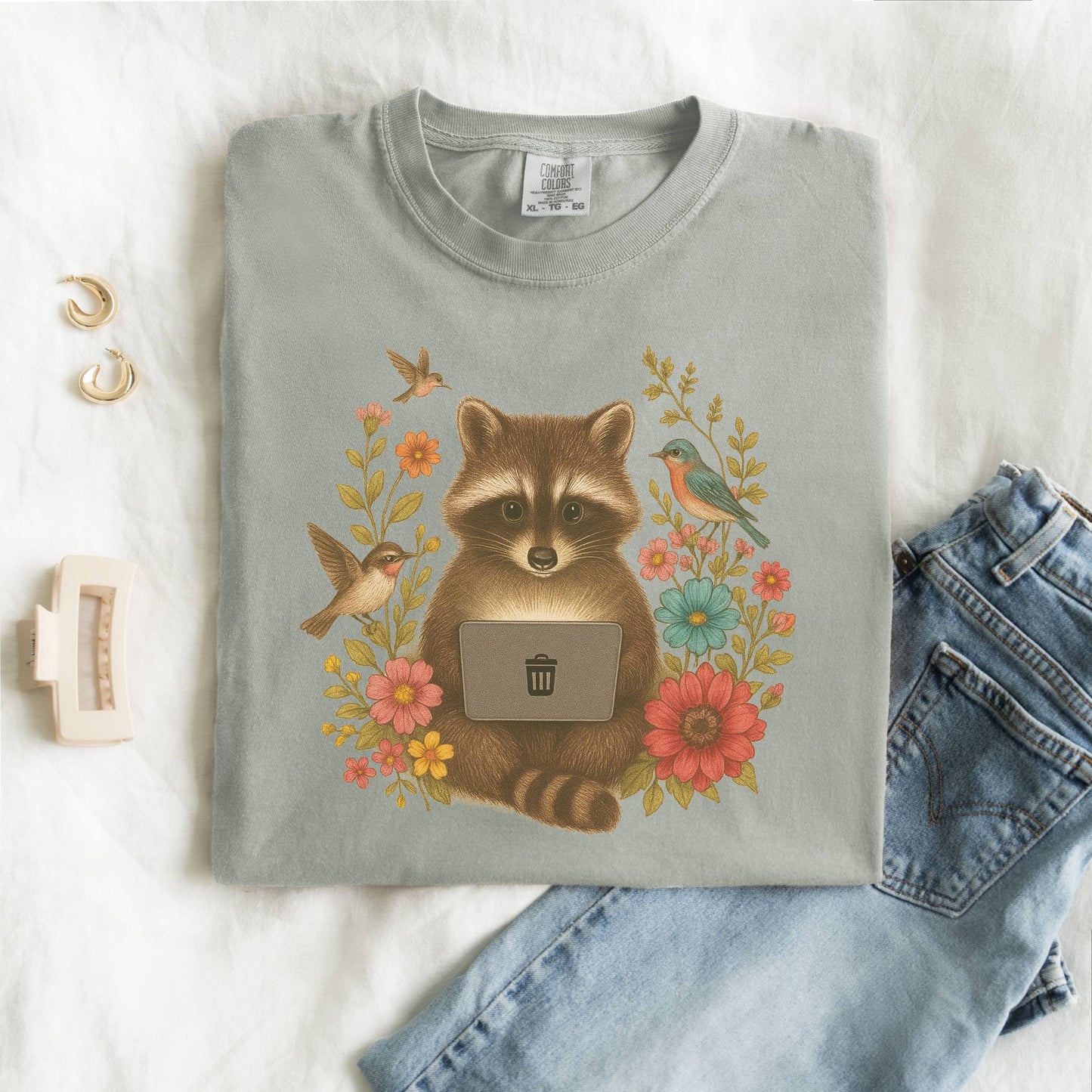 T-shirt with vintage-style raccoon illustration surrounded by colorful wildflowers and birds