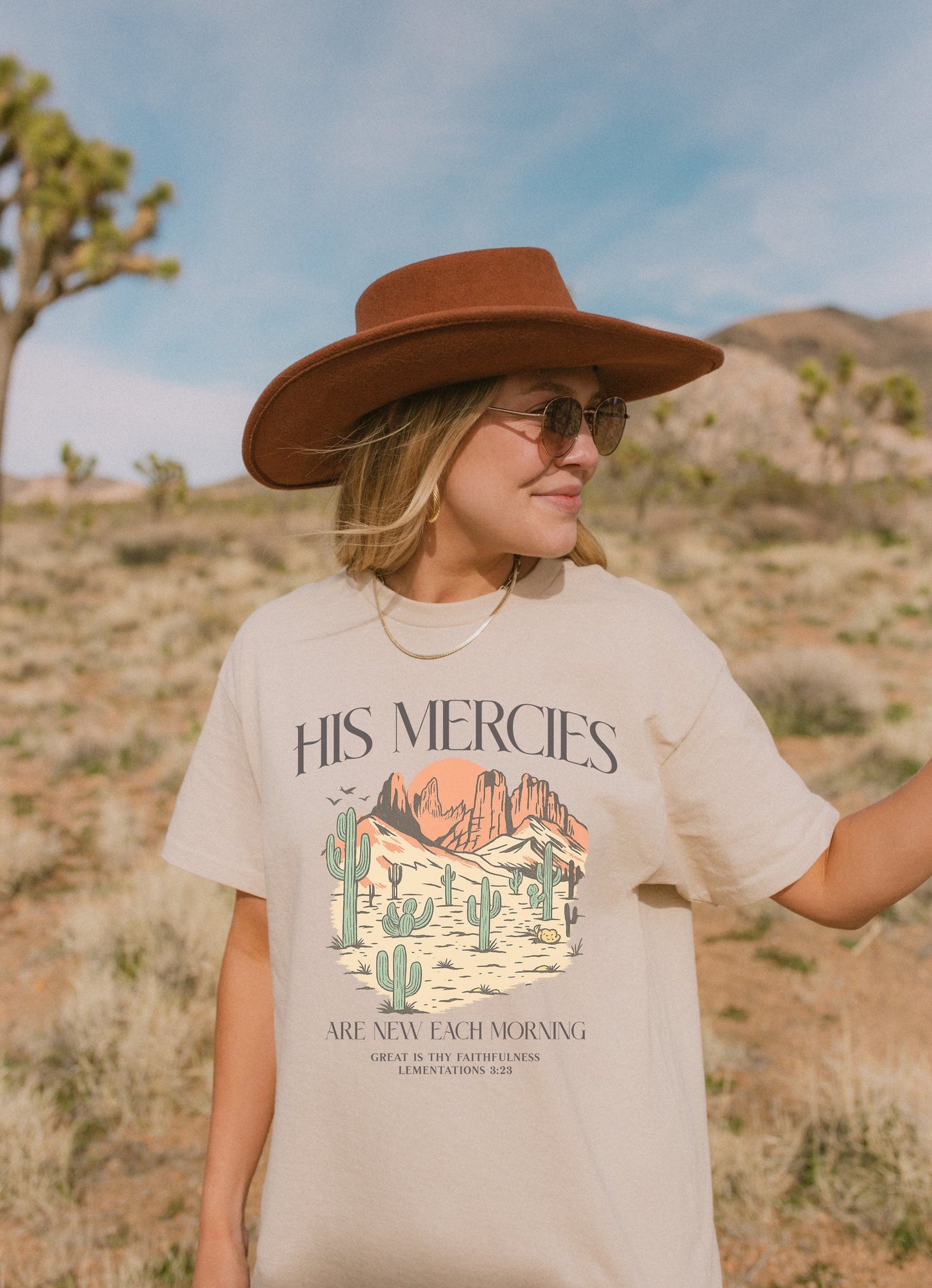 T-shirt with desert landscape design featuring cacti, mountains, and 'His Mercies Are New Each Morning' text with Lamentations 3:23 bible verse