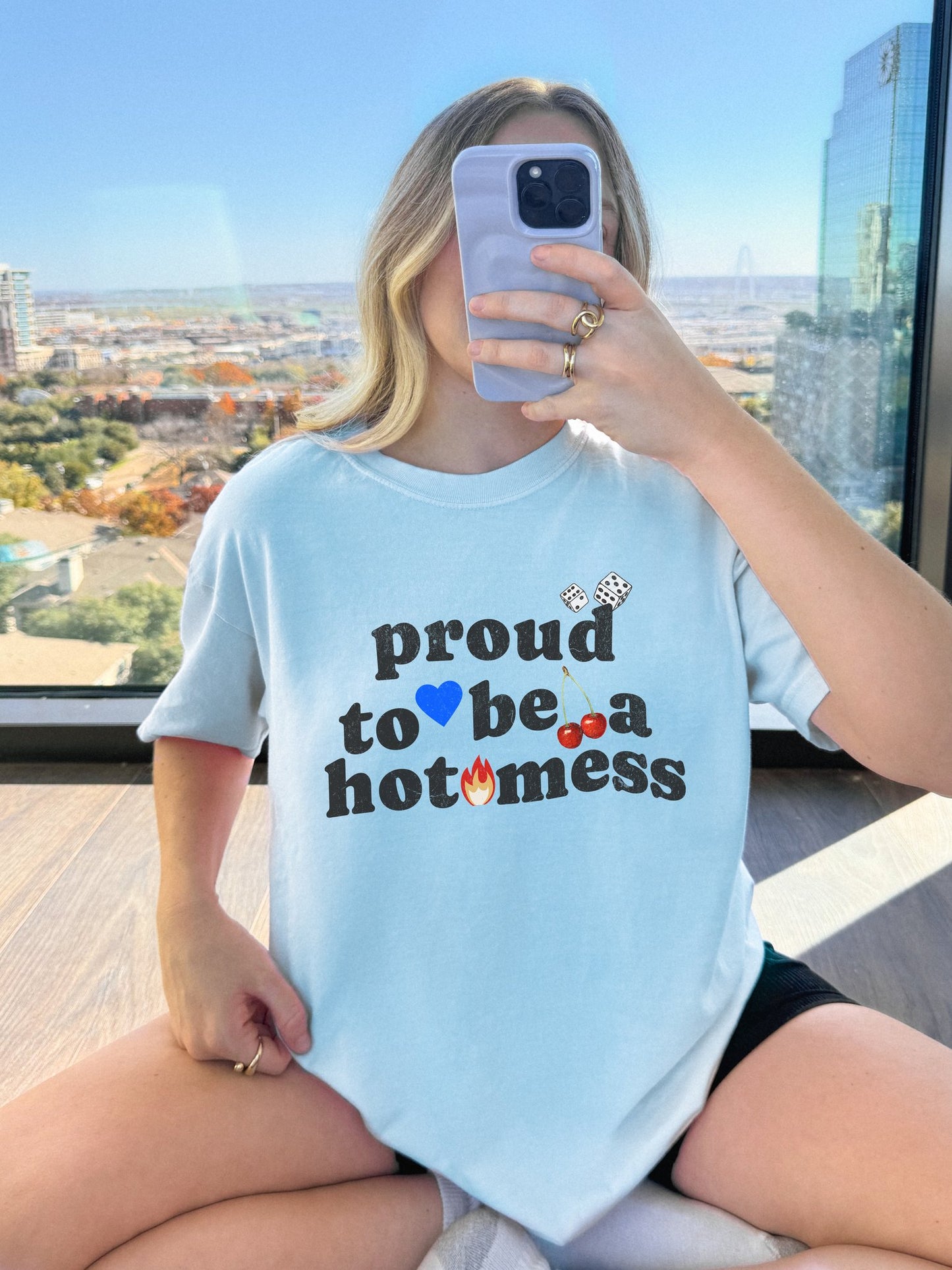 T-shirt with distressed black text reading 'proud to be a hot mess' decorated with dice, blue heart, cherries, and flame graphics