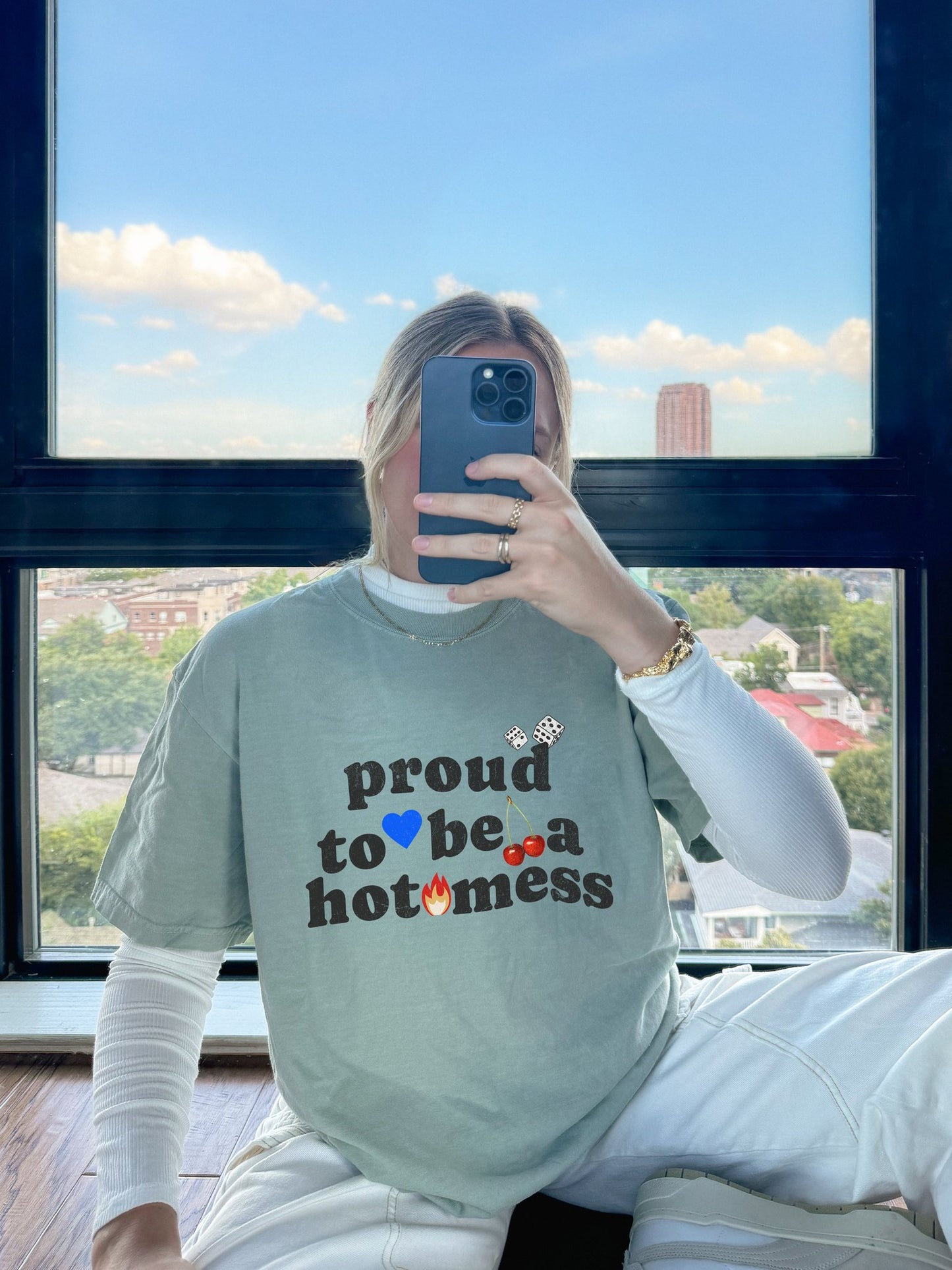 T-shirt with distressed black text reading 'proud to be a hot mess' decorated with dice, blue heart, cherries, and flame graphics