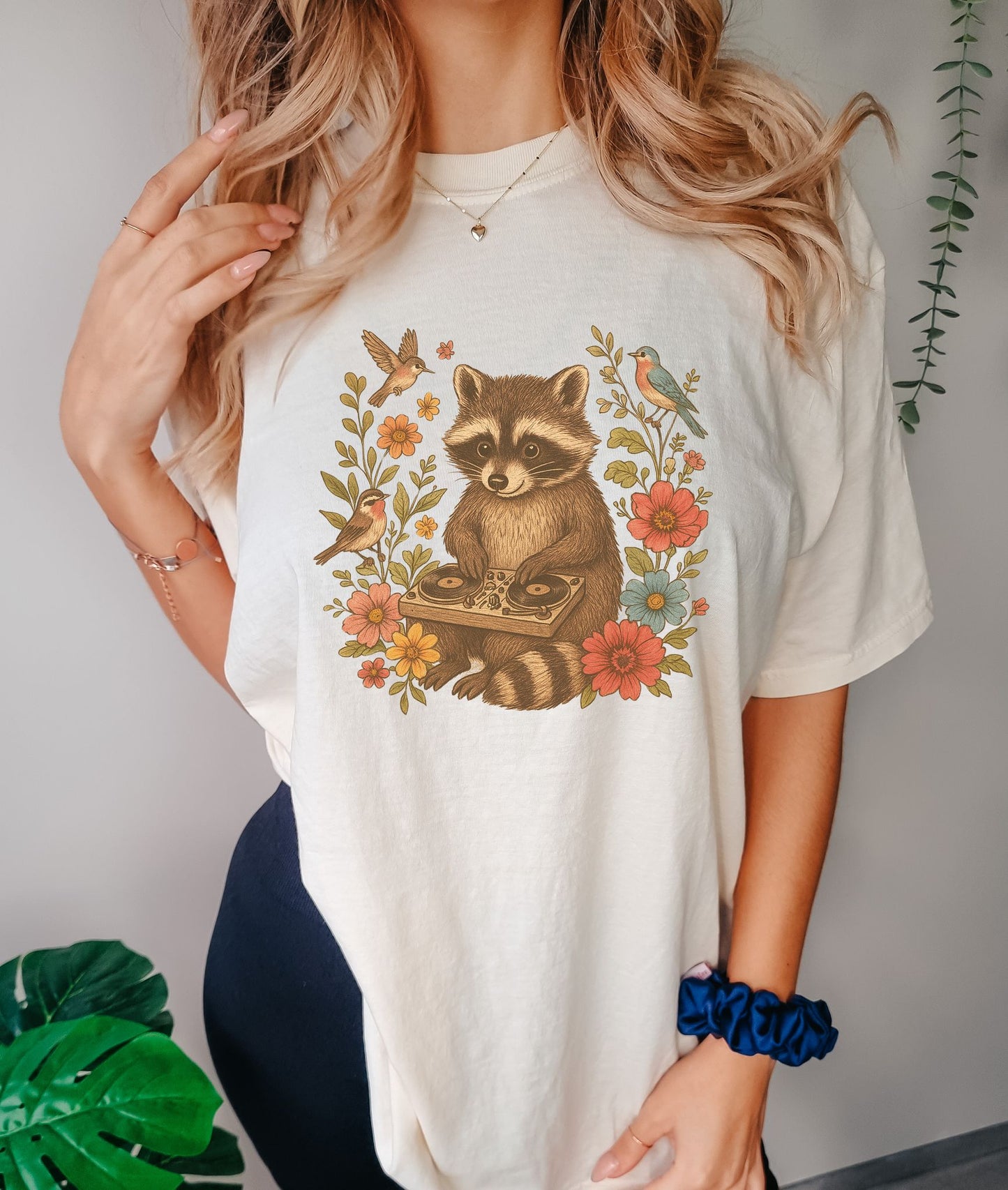 T-shirt with vintage raccoon DJ design surrounded by coral flowers, yellow blooms, and songbirds