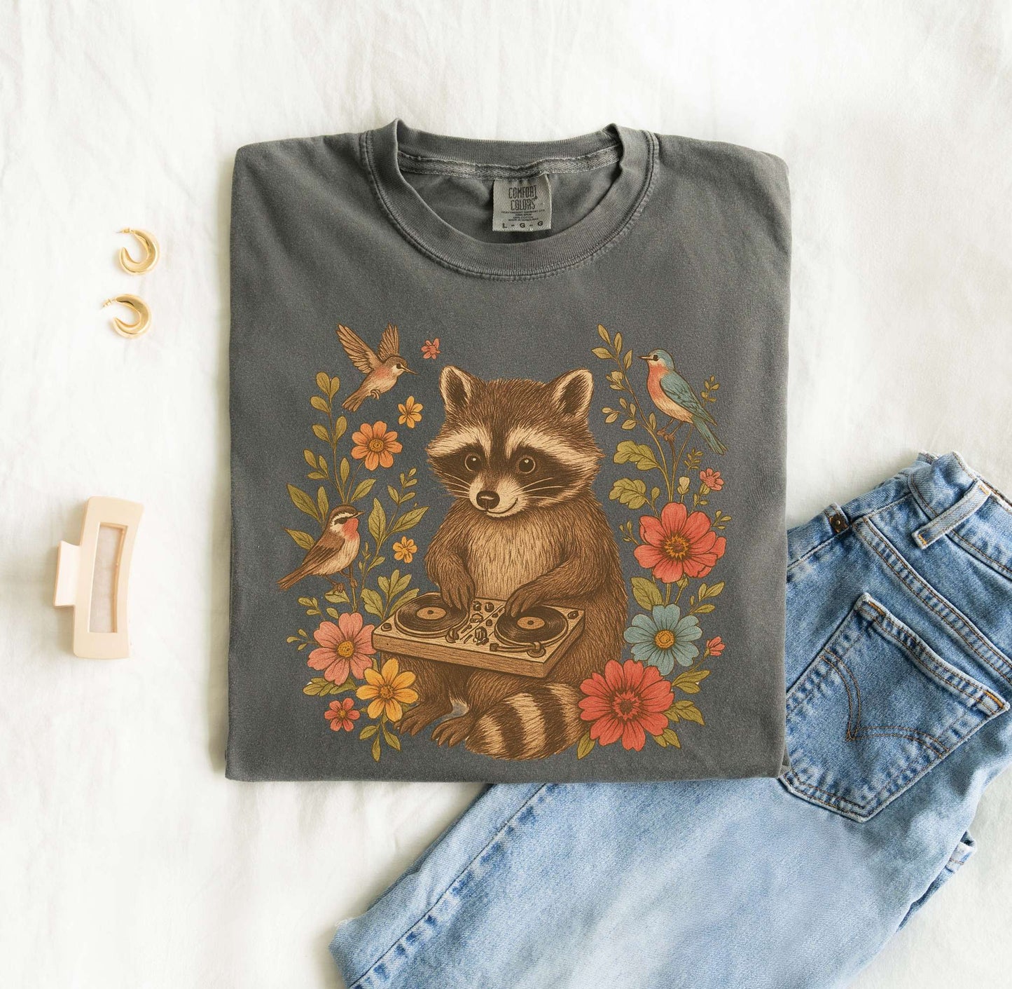 T-shirt with vintage raccoon DJ design surrounded by coral flowers, yellow blooms, and songbirds