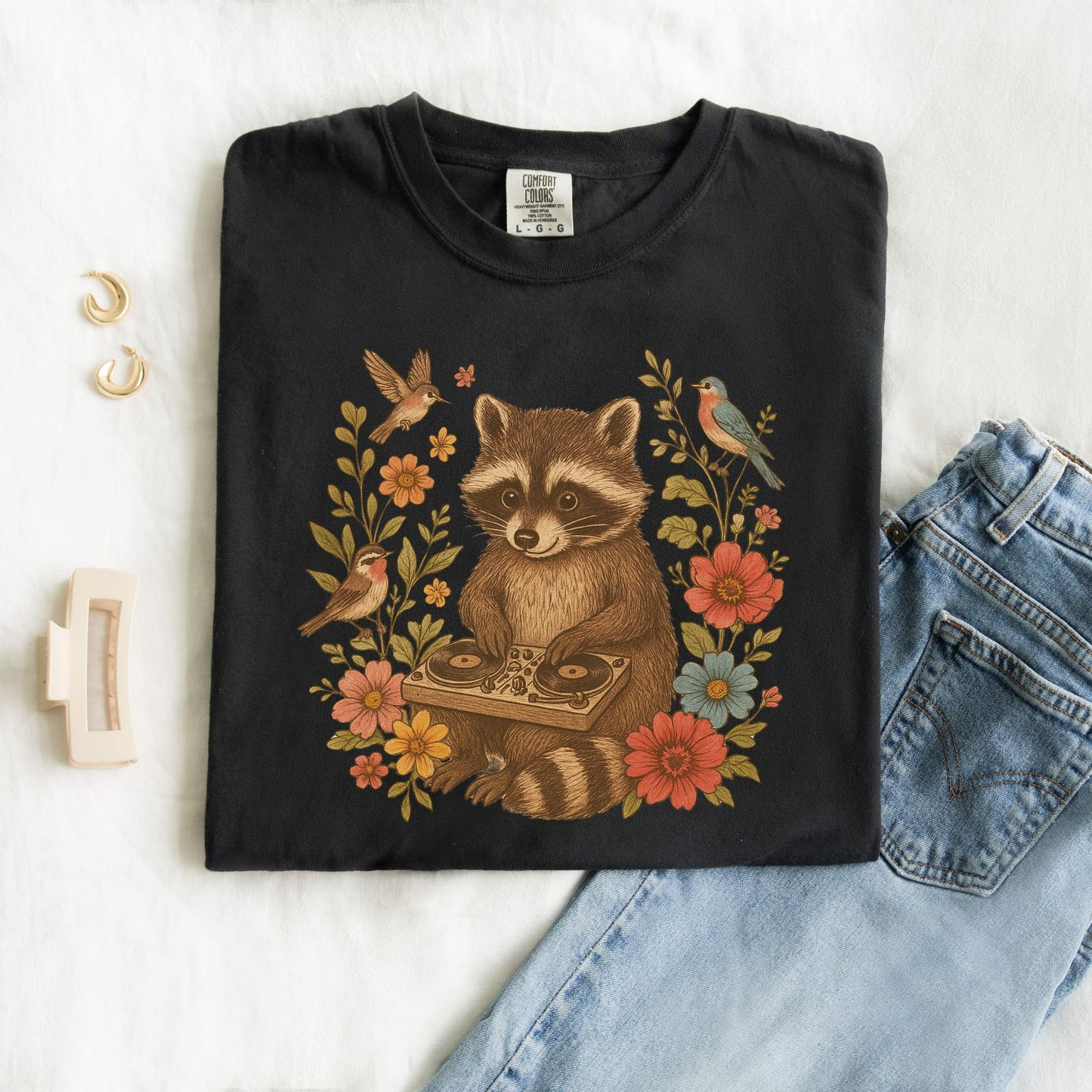 T-shirt with vintage raccoon DJ design surrounded by coral flowers, yellow blooms, and songbirds