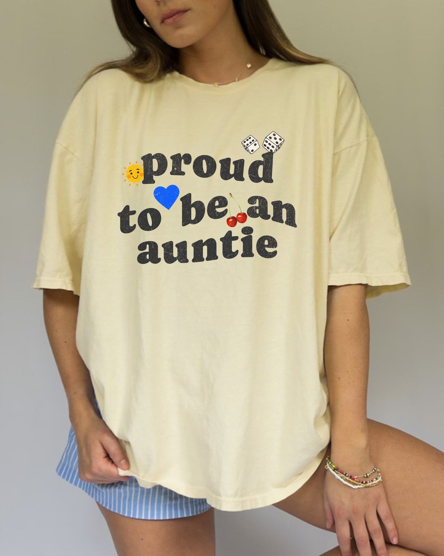 T-shirt with distressed text 'proud to be an auntie' featuring sun, heart, dice and cherries