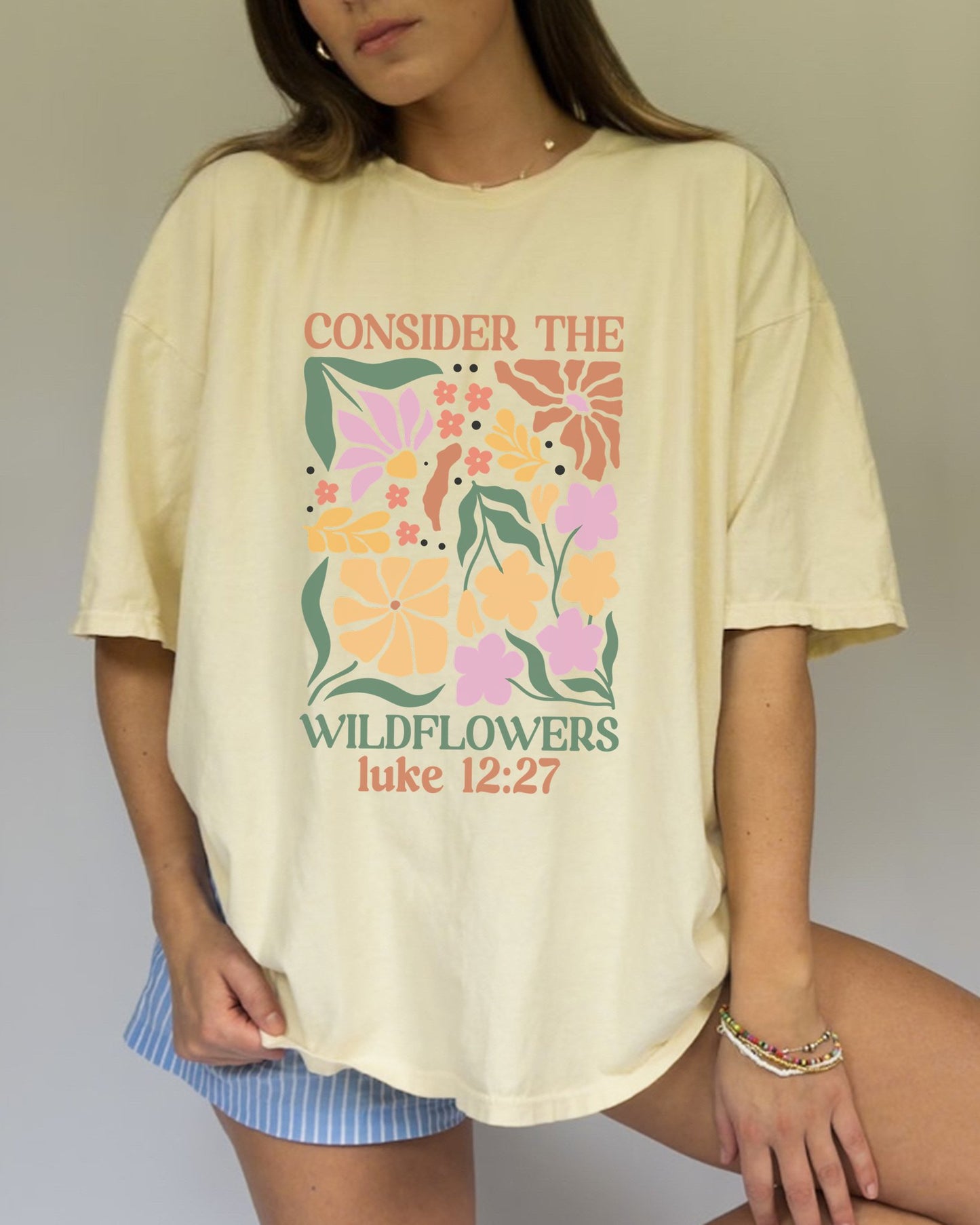 T-shirt with colorful wildflower design and 'Consider the Wildflowers Luke 12:27' bible verse text