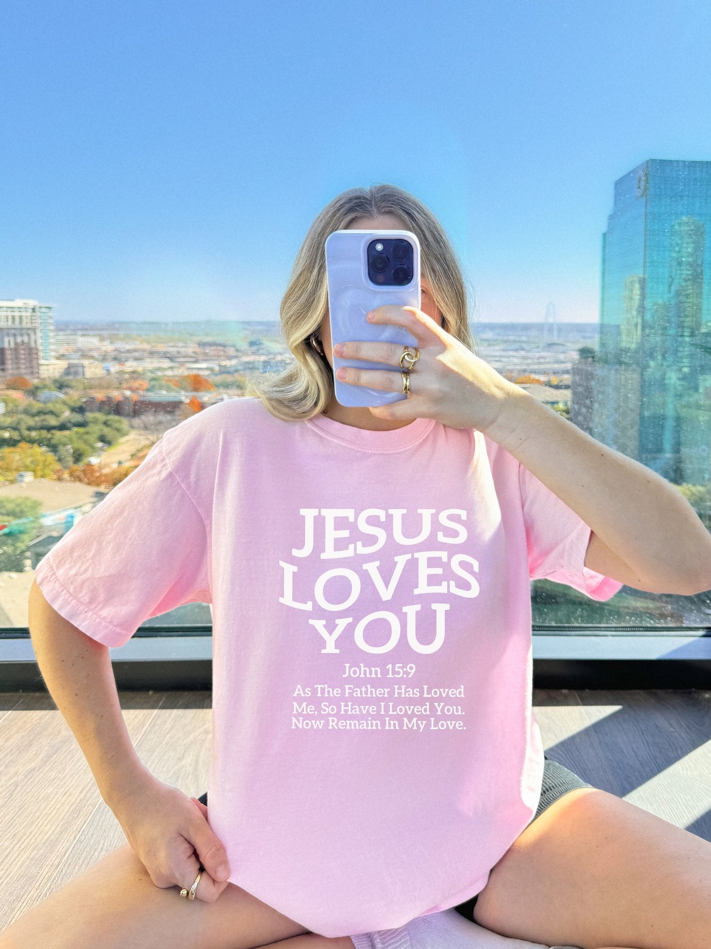 Black text design on t-shirt reading Jesus Loves You with John 15:9 Bible verse
