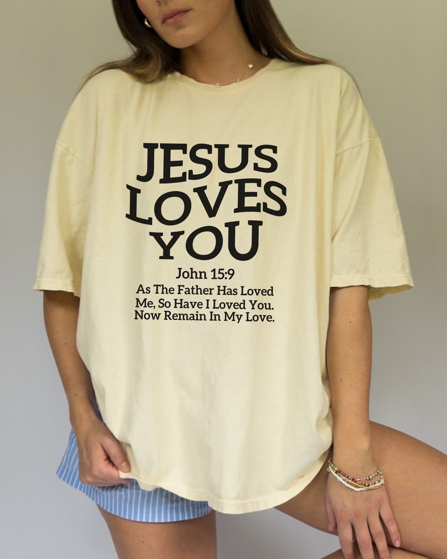 Black text design on t-shirt reading Jesus Loves You with John 15:9 Bible verse