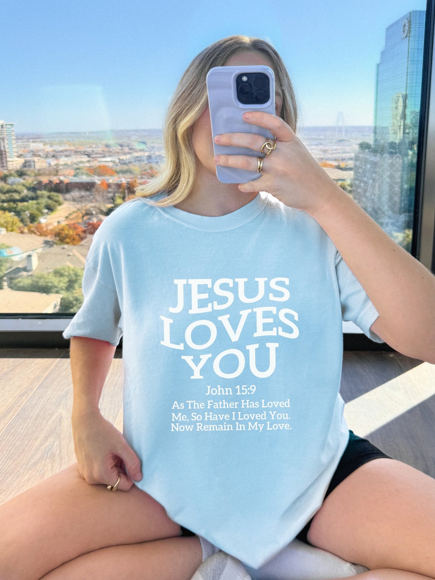 Black text design on t-shirt reading Jesus Loves You with John 15:9 Bible verse