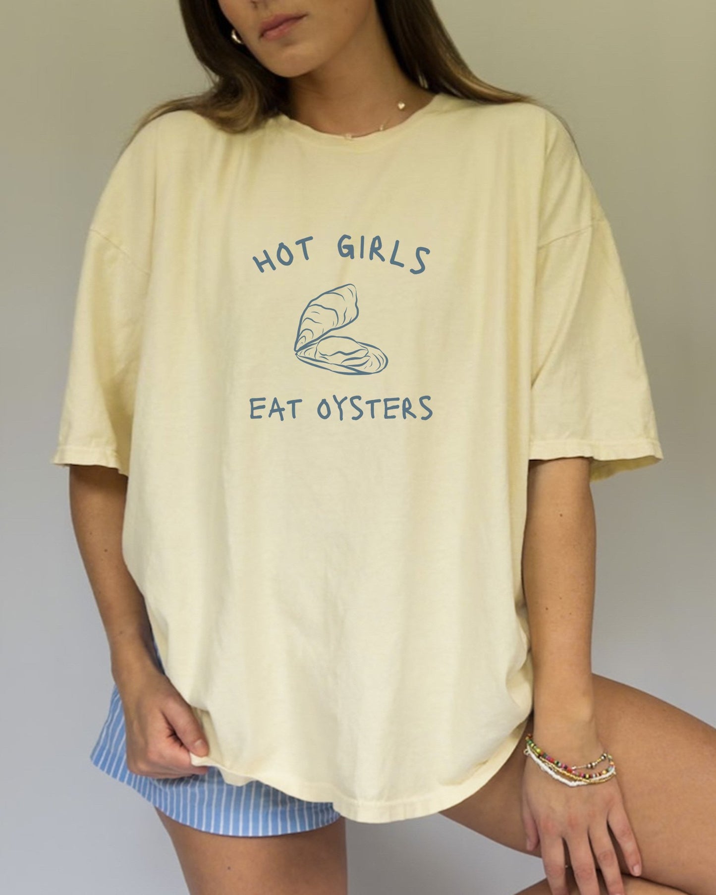 T-shirt with 'Hot Girls Eat Oysters' text and minimalist oyster shell illustration in blue tones