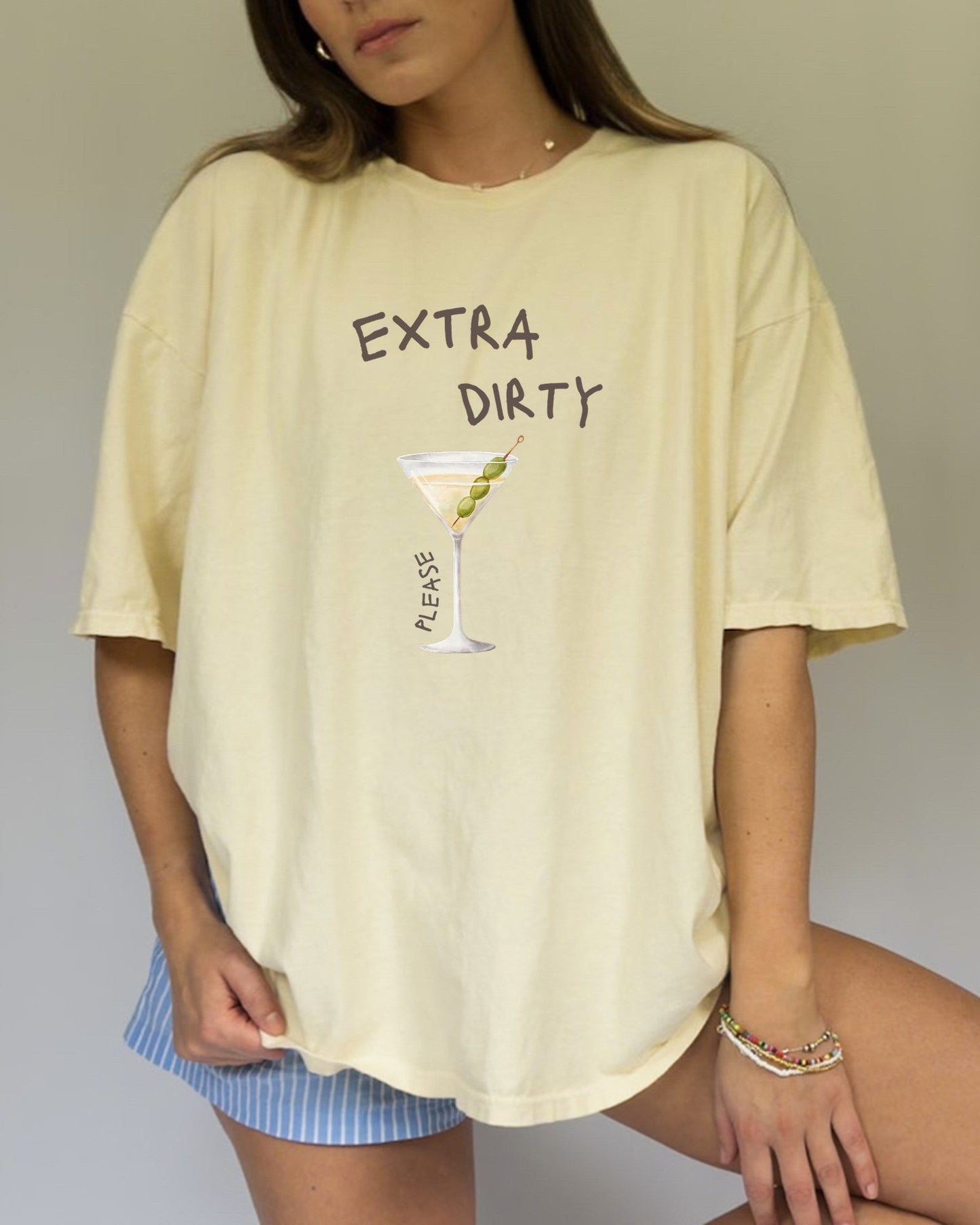 T-shirt design with martini glass filled with clear liquid and three green olives on a pick