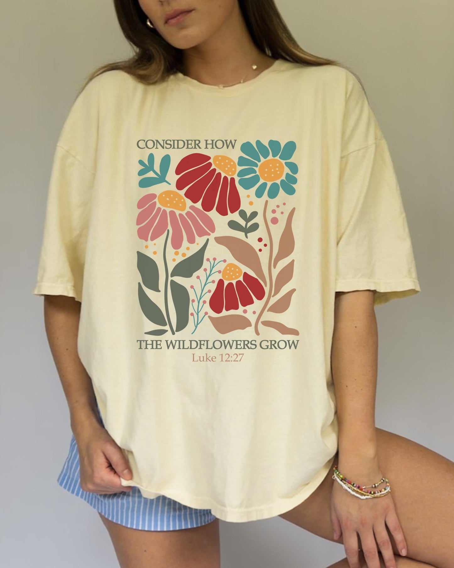 T-shirt with Luke 12:27 Bible verse and colorful wildflowers in red, pink, teal, and brown tones