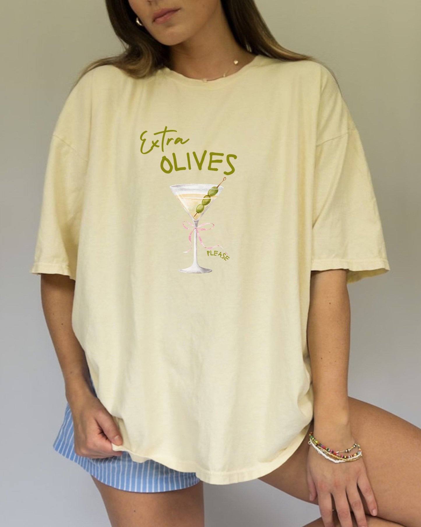 T-shirt design with martini glass, green olives, and pink bow saying Extra Olives Please