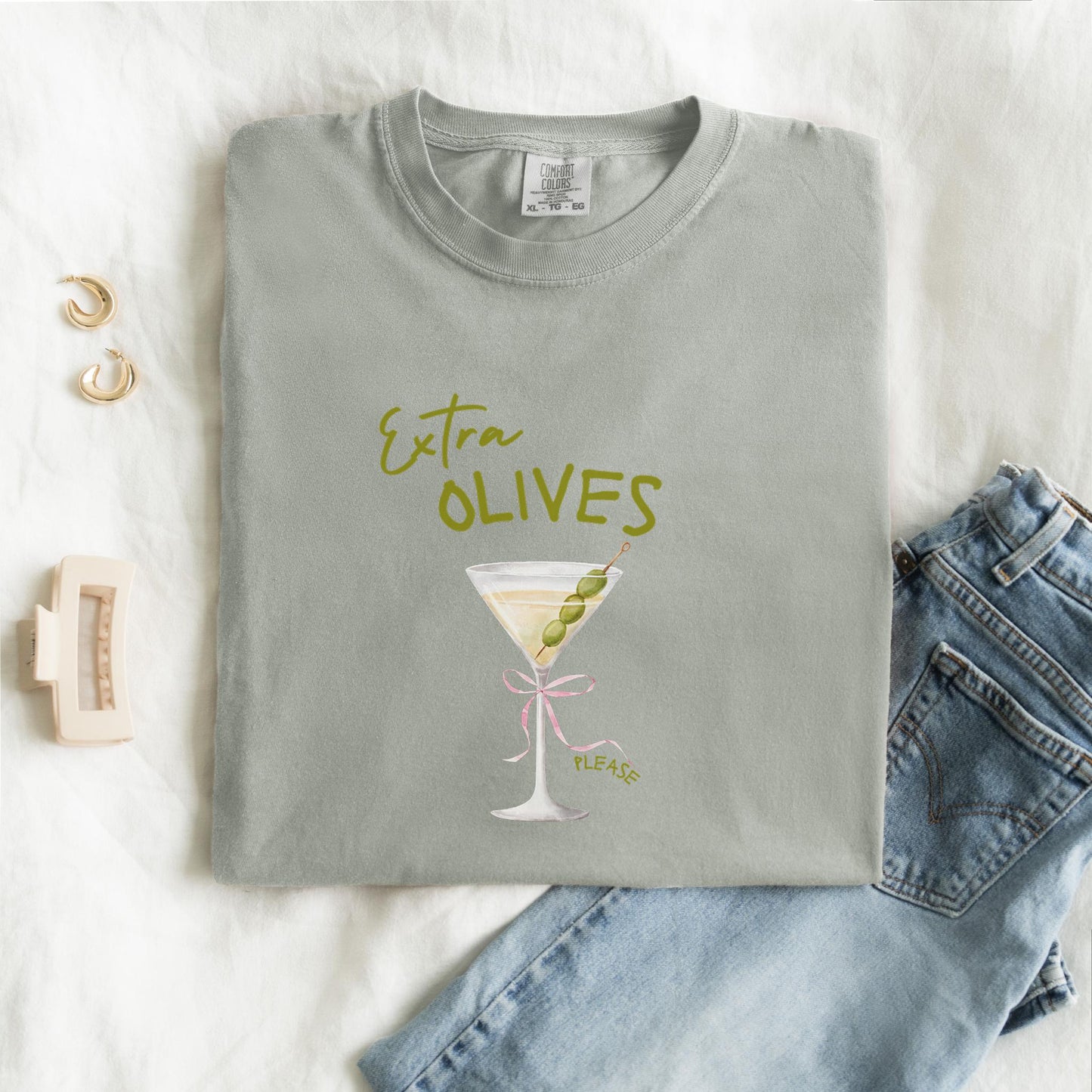T-shirt design with martini glass, green olives, and pink bow saying Extra Olives Please