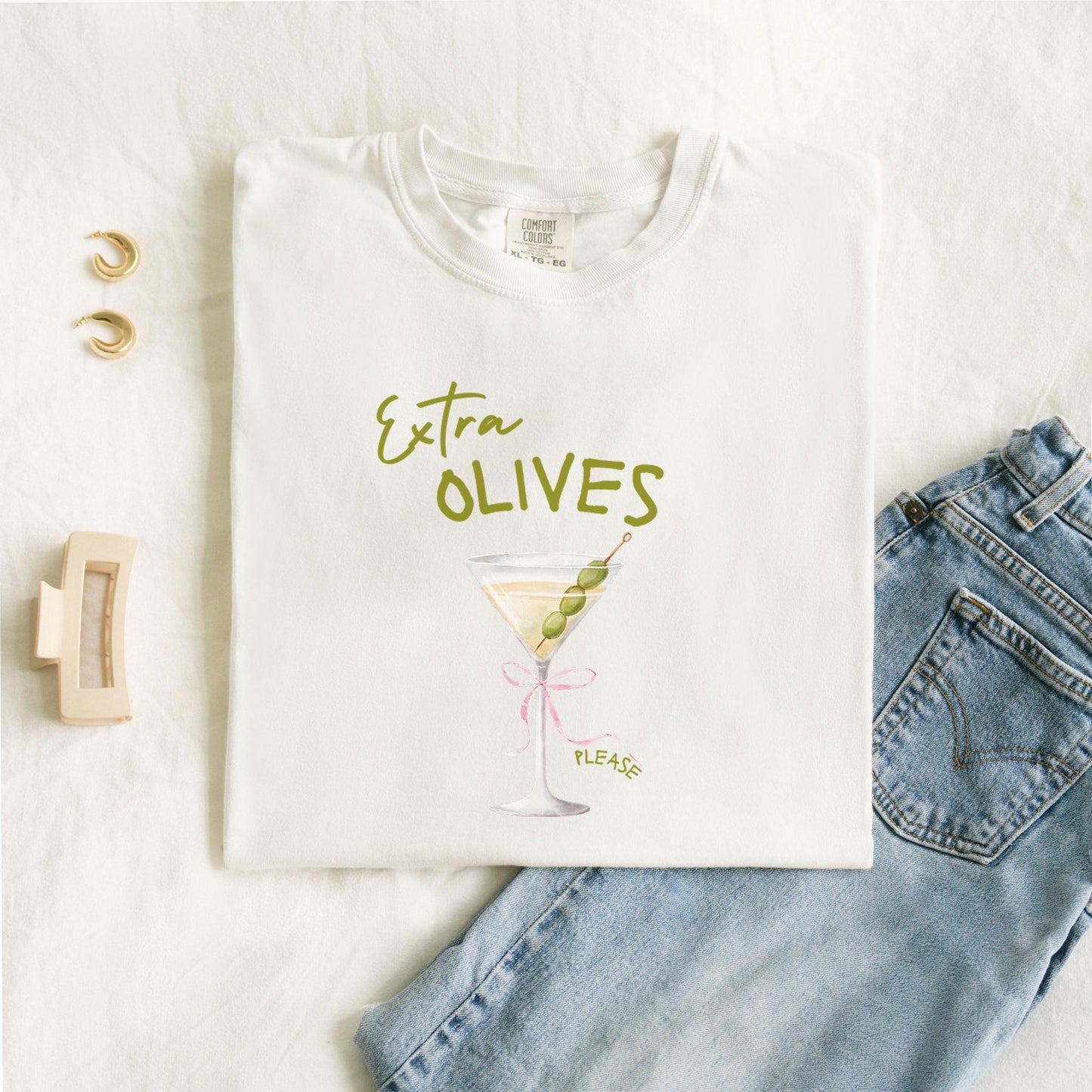 T-shirt design with martini glass, green olives, and pink bow saying Extra Olives Please