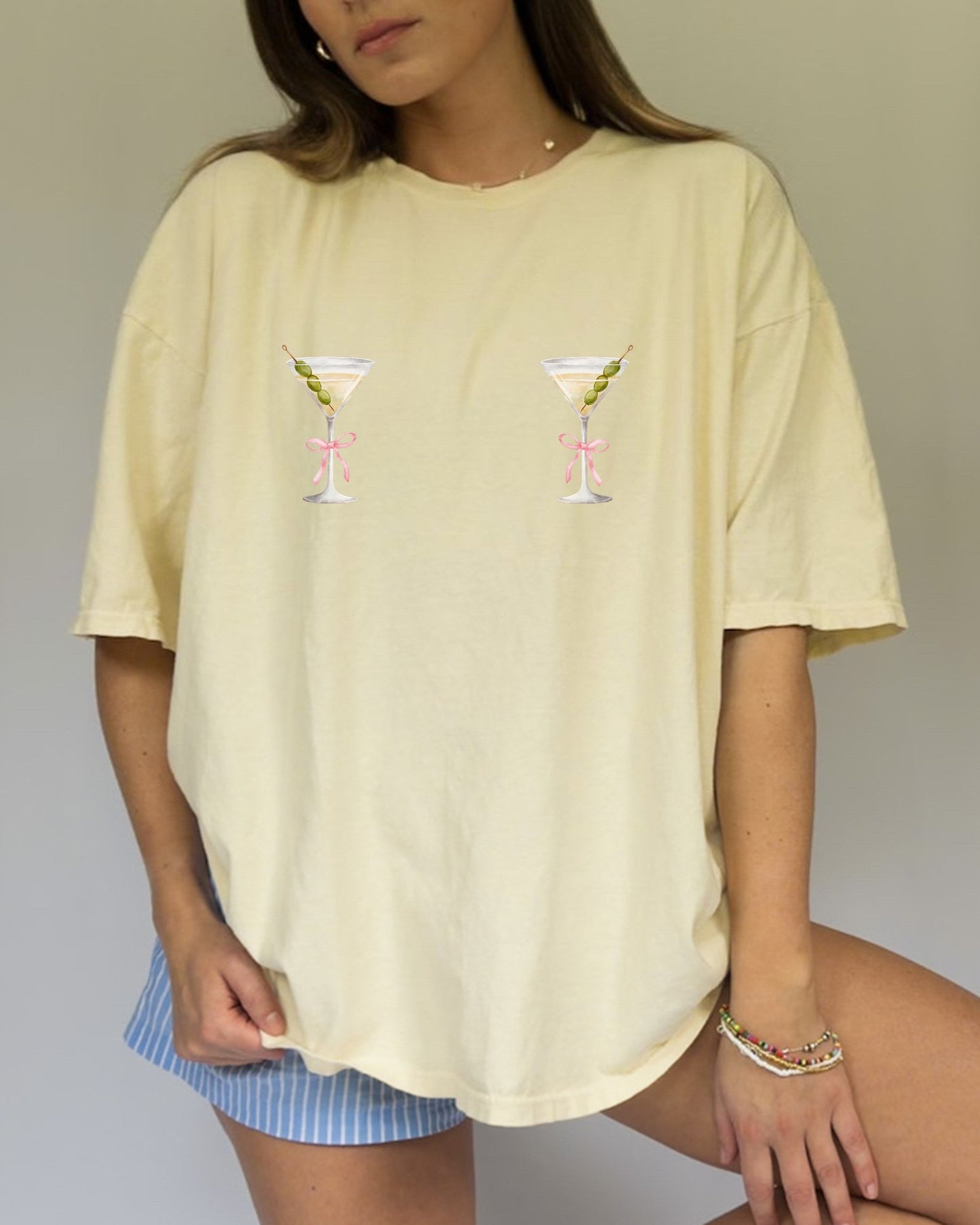 T-shirt design with two martini glasses containing olives and pink bow details creating a humorous cocktail theme