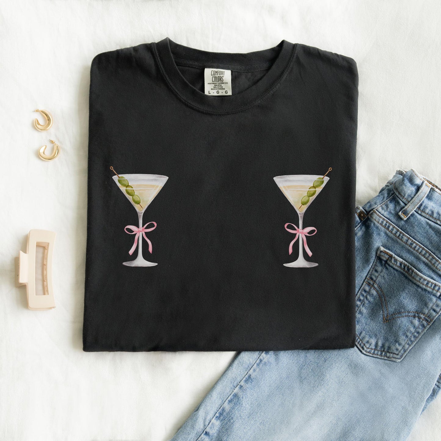 T-shirt design with two martini glasses containing olives and pink bow details creating a humorous cocktail theme