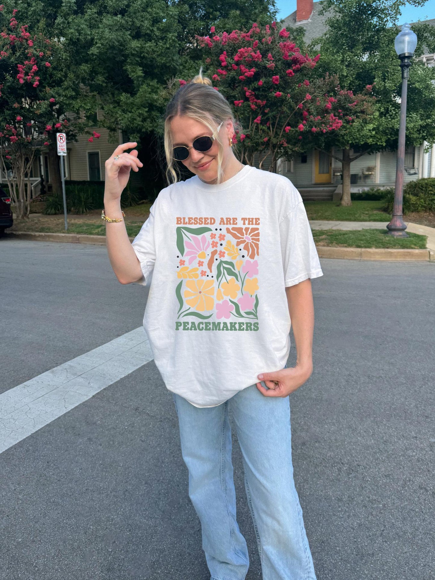 T-shirt with 'Blessed Are The Peacemakers' text surrounded by colorful floral design in pink, coral, yellow and green
