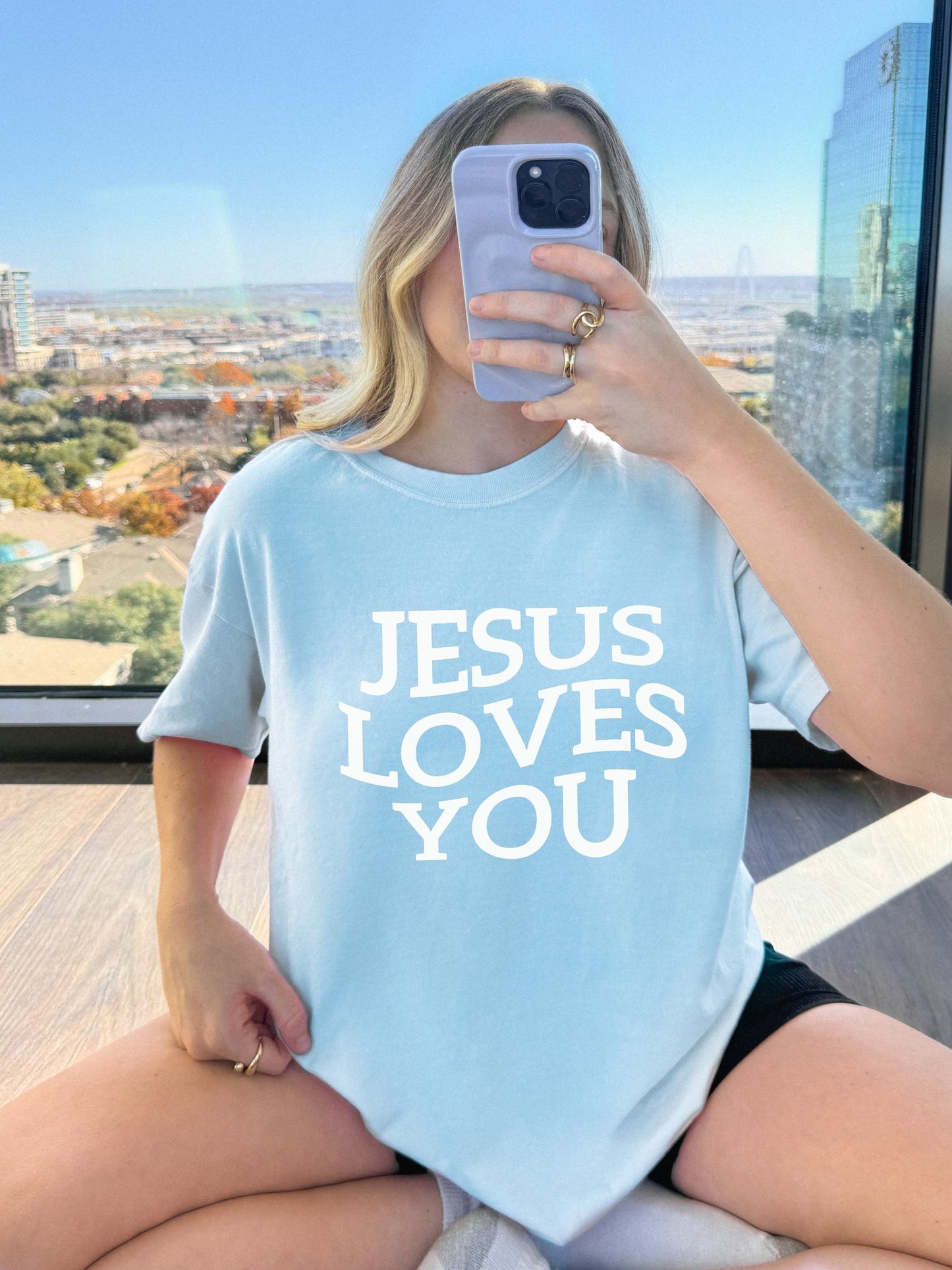 T-shirt with bold black text reading 'JESUS LOVES YOU' in large serif typography