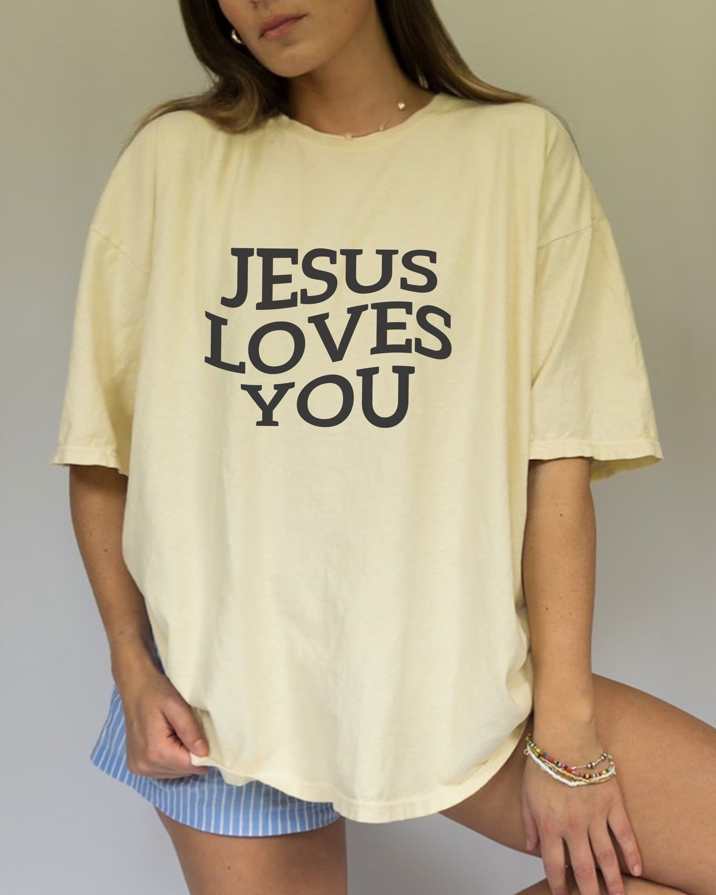 T-shirt with bold black text reading 'JESUS LOVES YOU' in large serif typography