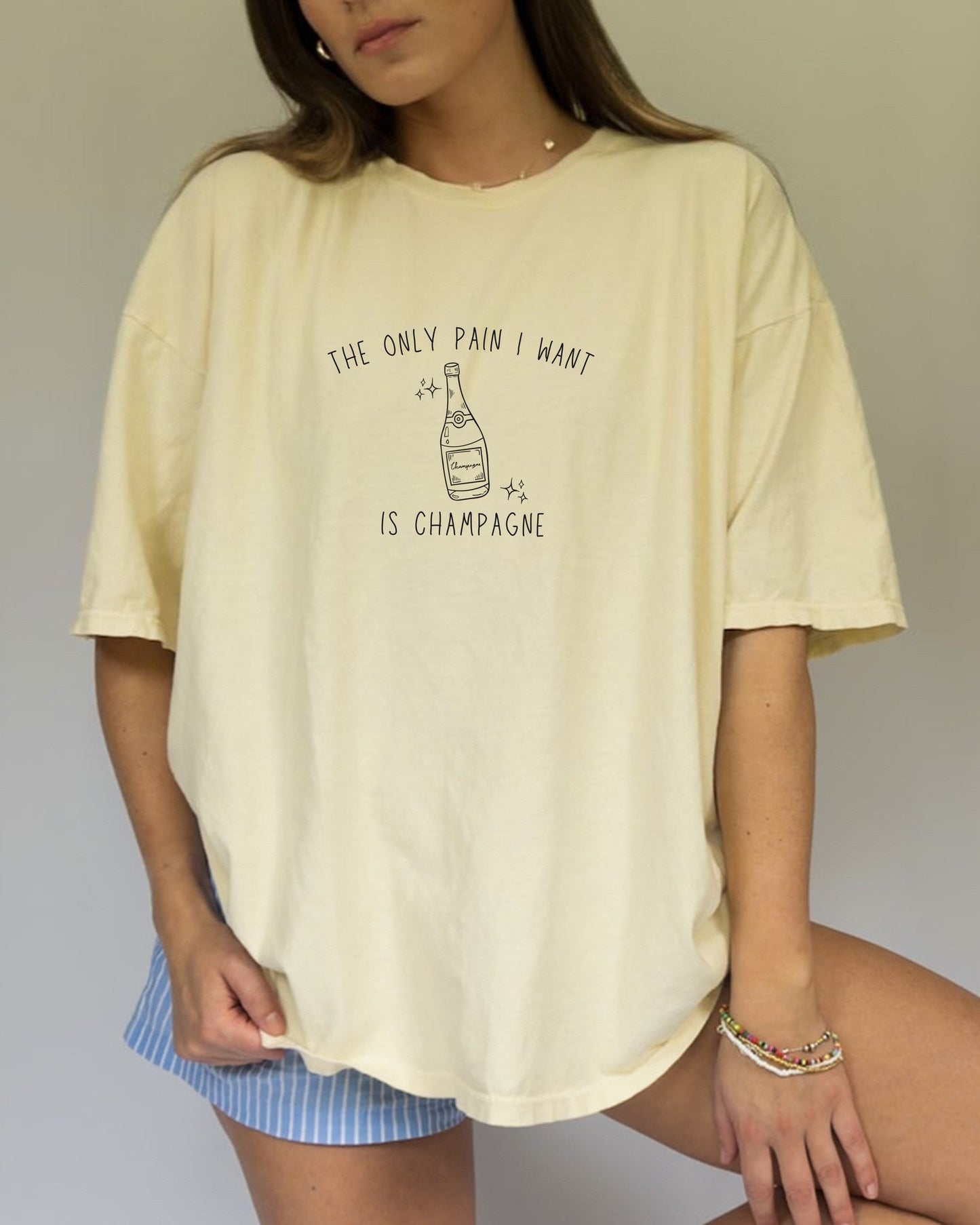 T-shirt with champagne bottle illustration and text 'The Only Pain I Want Is Champagne'