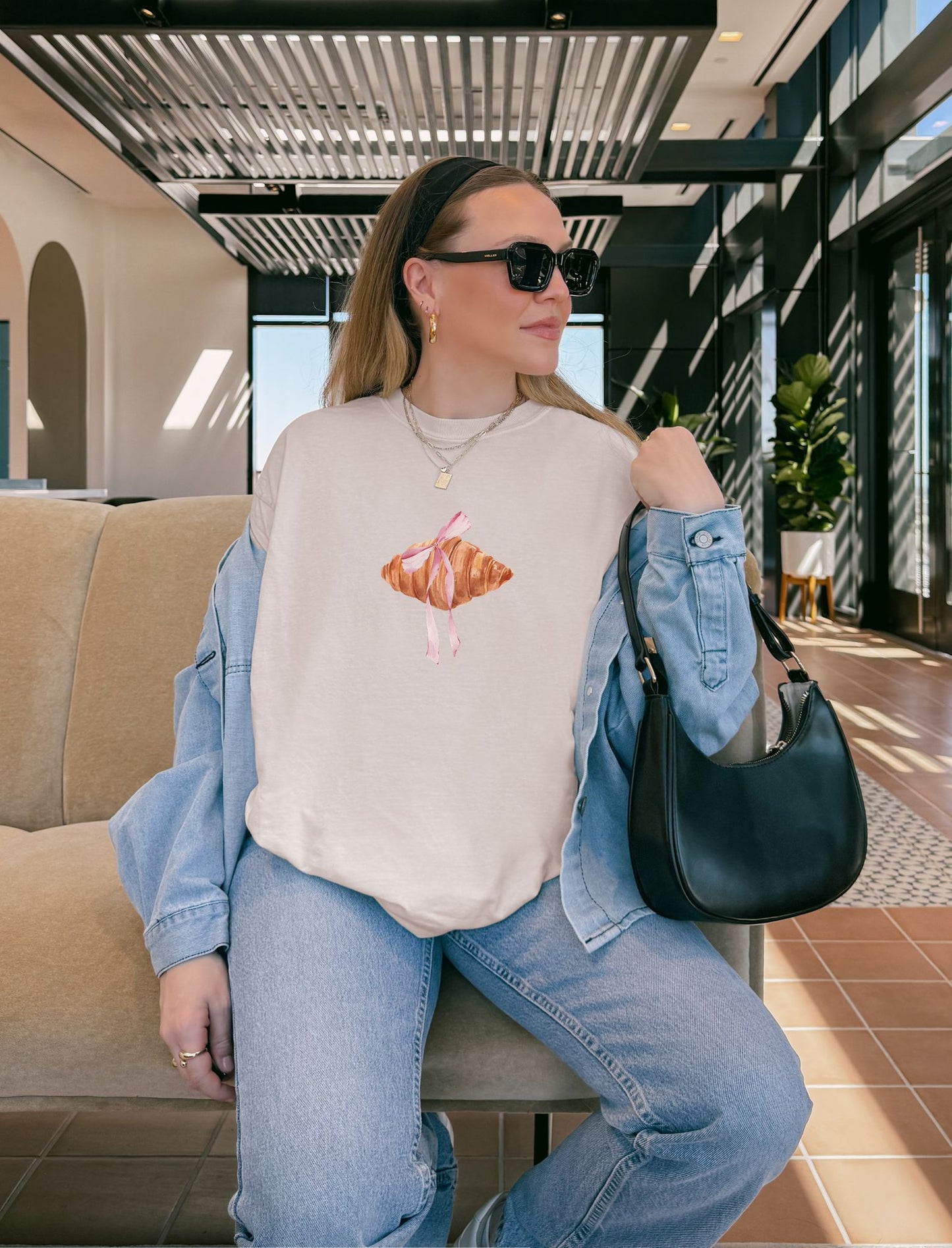 T-shirt with watercolor croissant design featuring golden brown pastry with pink ribbon bow