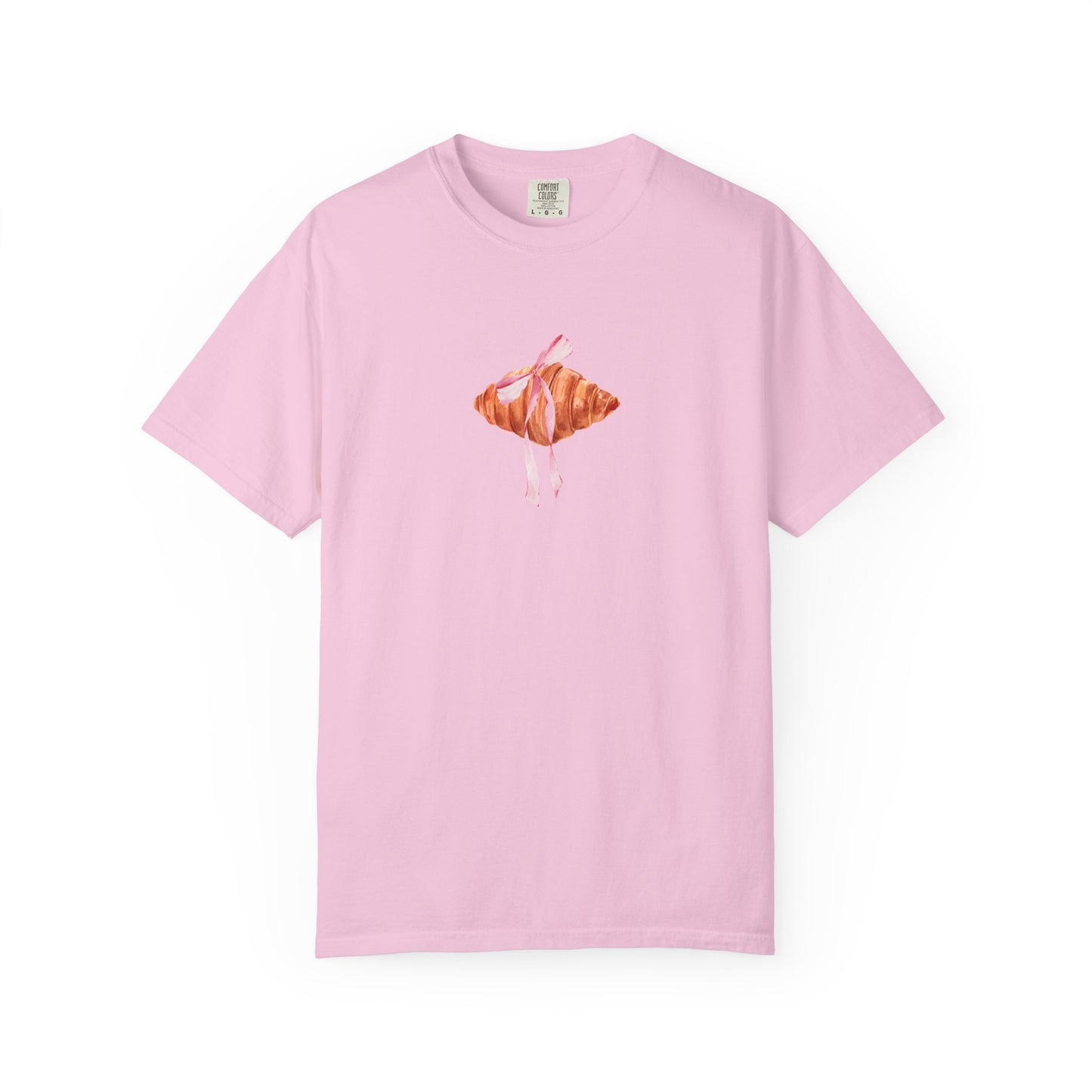 T-shirt with watercolor croissant design featuring golden brown pastry with pink ribbon bow