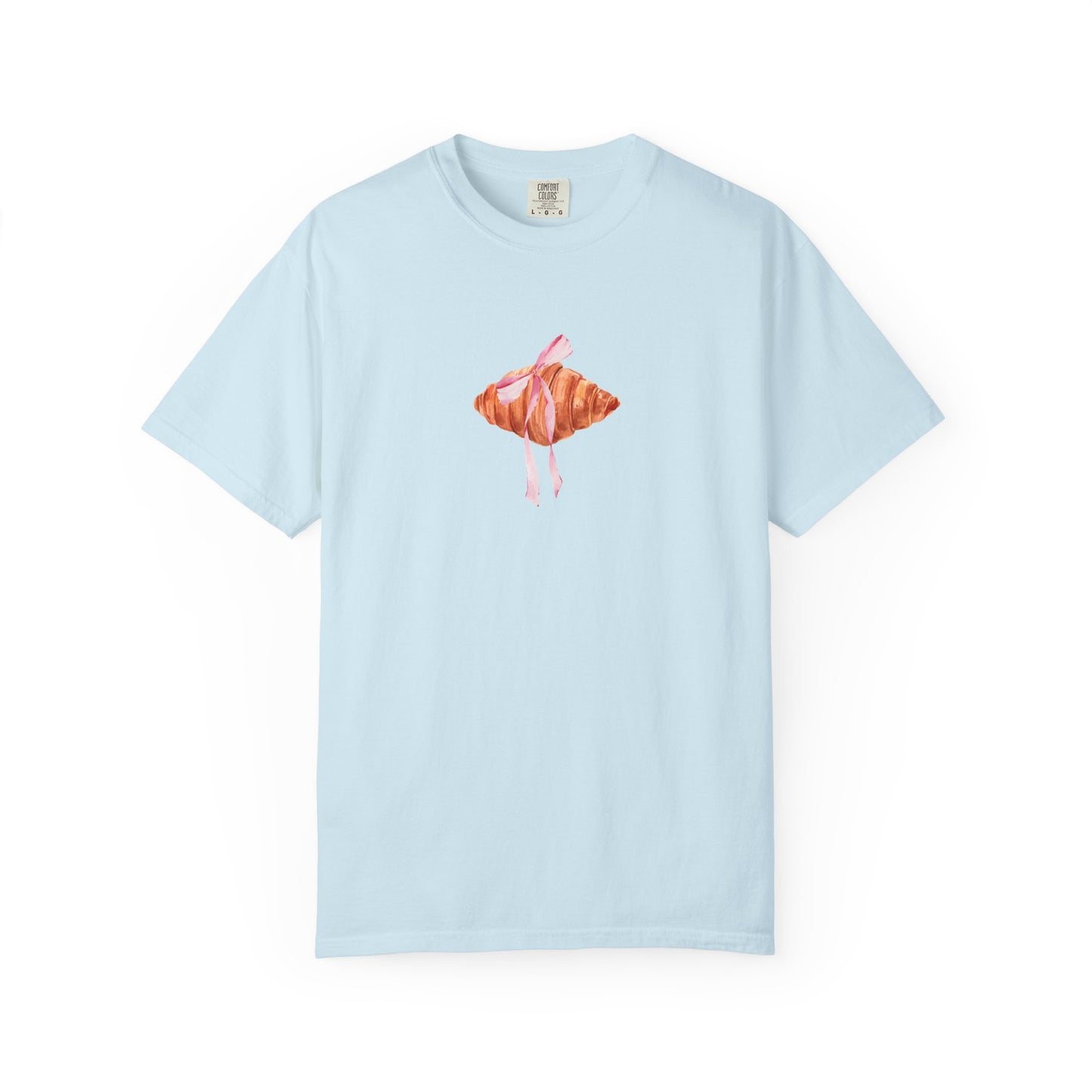 T-shirt with watercolor croissant design featuring golden brown pastry with pink ribbon bow