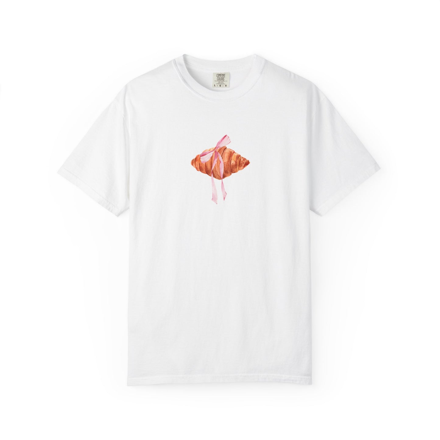 T-shirt with watercolor croissant design featuring golden brown pastry with pink ribbon bow