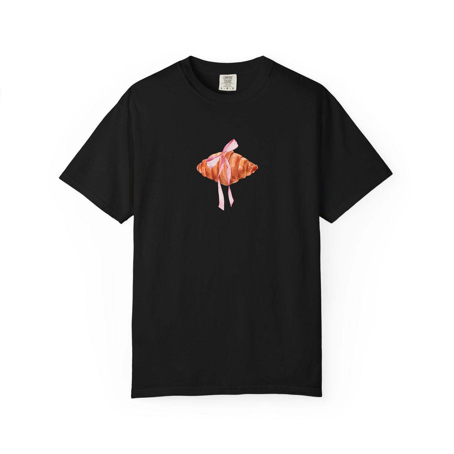 T-shirt with watercolor croissant design featuring golden brown pastry with pink ribbon bow
