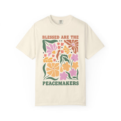 T-shirt with 'Blessed Are The Peacemakers' text surrounded by colorful floral design in pink, coral, yellow and green