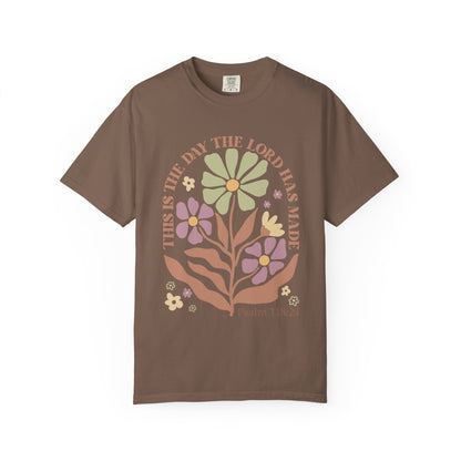 T-shirt with 'This is the Day' text, Psalm 118:24 verse, and floral design with protective hands in sage green, pink, and terracotta colors