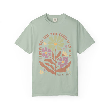 T-shirt with 'This is the Day' text, Psalm 118:24 verse, and floral design with protective hands in sage green, pink, and terracotta colors