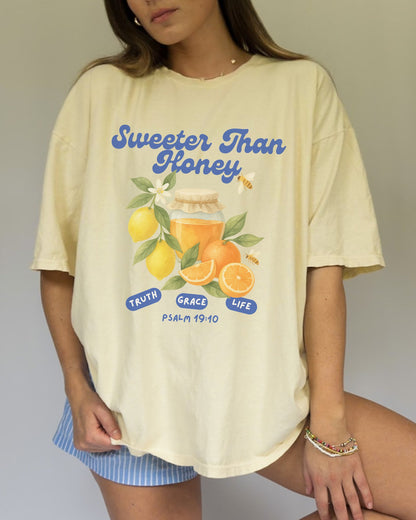 Christian t-shirt with Sweeter Than Honey Psalm 19:10 design featuring watercolor honey jar, citrus fruits, and bees