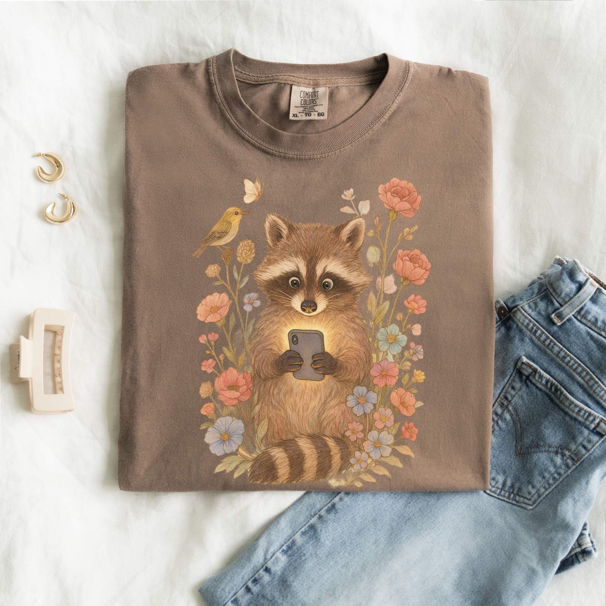 T-shirt with cute raccoon holding smartphone surrounded by coral and blue wildflowers