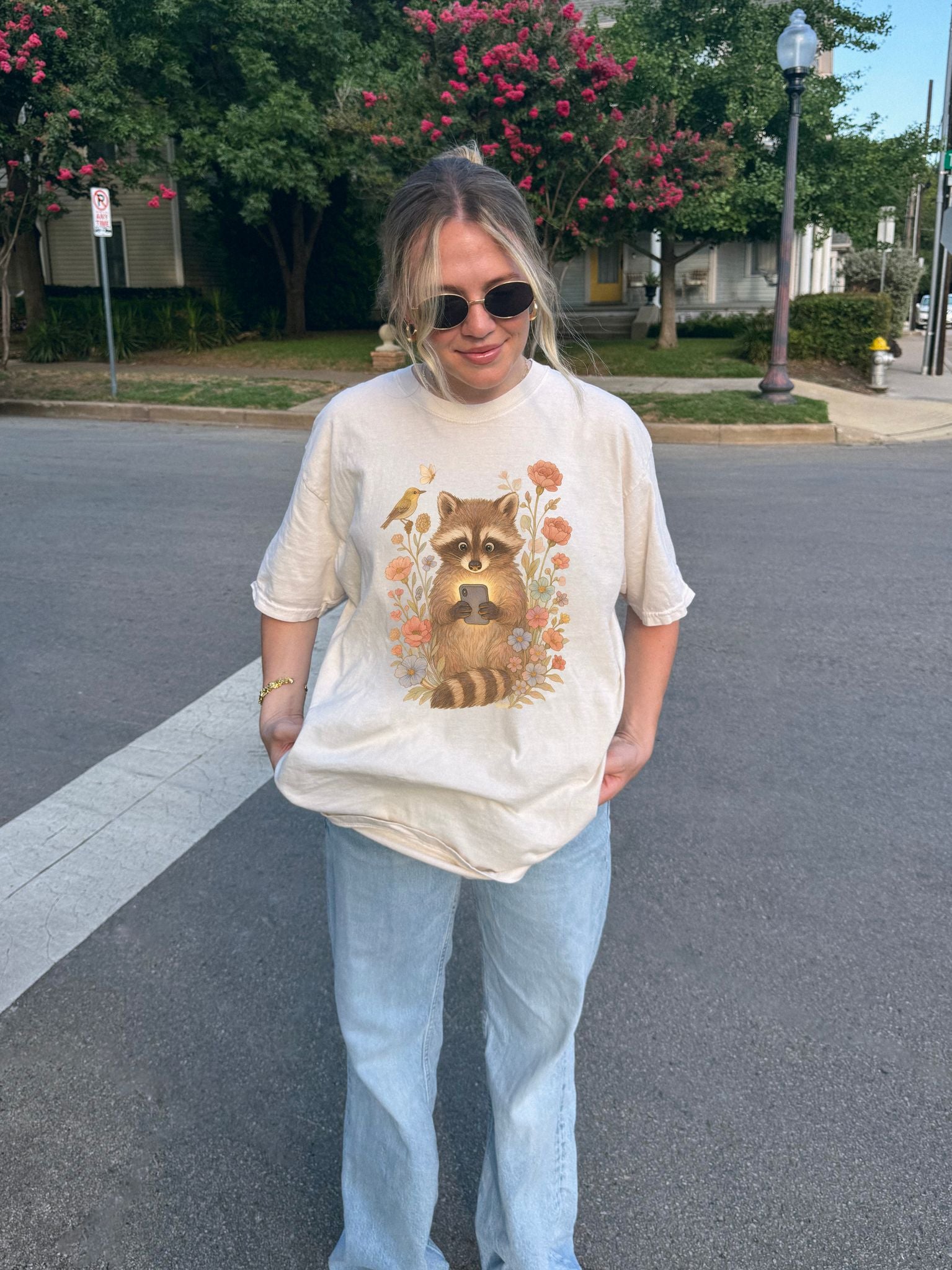 T-shirt with cute raccoon holding smartphone surrounded by coral and blue wildflowers
