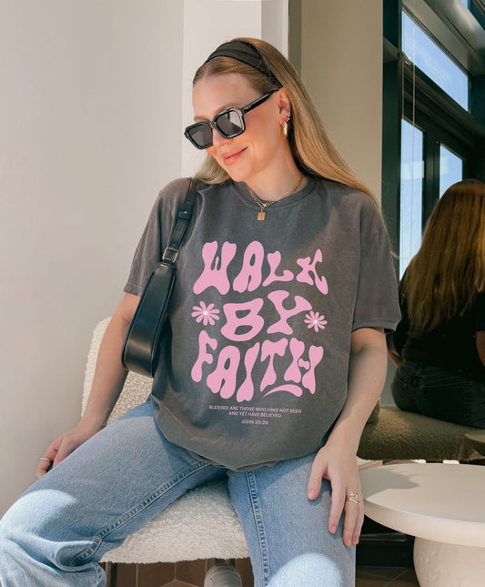 T-shirt with pink wavy font saying Walk By Faith with flowers and John 20:29 Bible verse