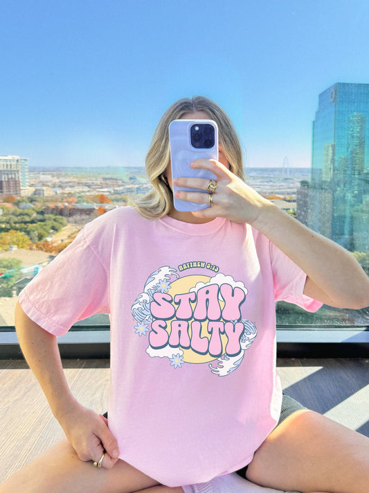 T-shirt with wavy font Stay Salty Matthew 5:13 text in pink bubble letters with ocean waves and flowers