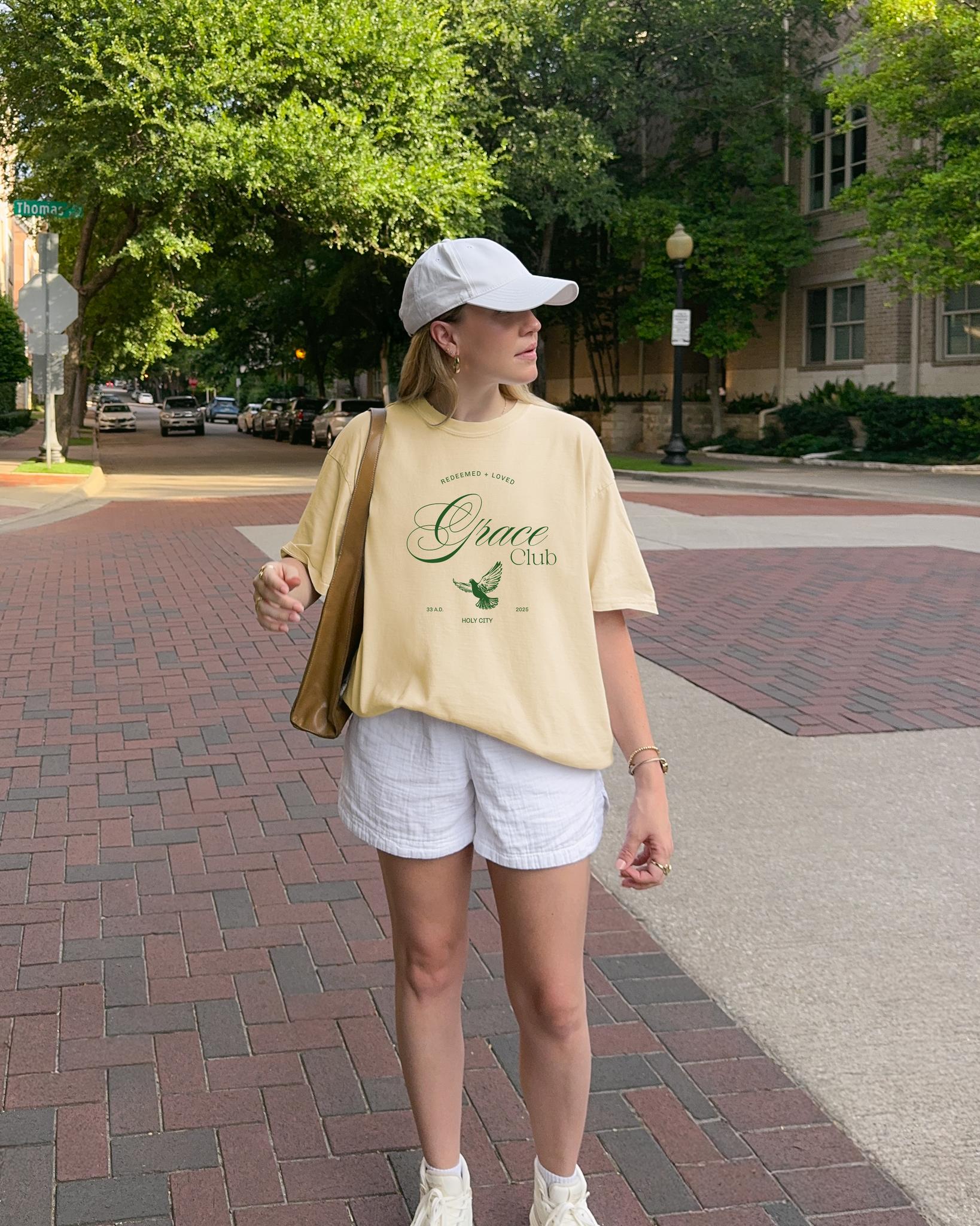 T-shirt with Grace Club text, dove symbol, and Redeemed + Loved message in elegant green design
